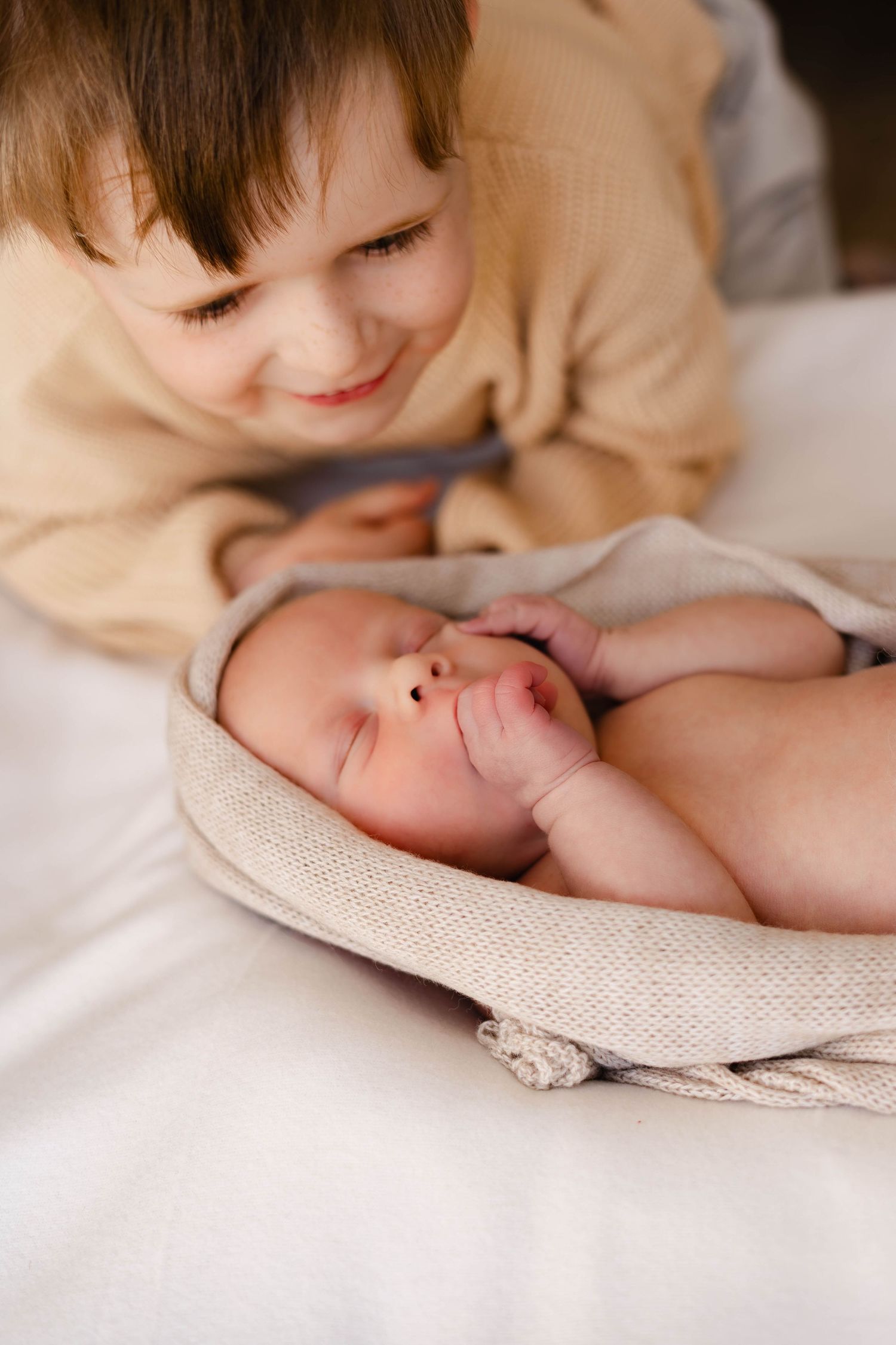 Intimate newborn photography session capturing tender family moments on white bedding.