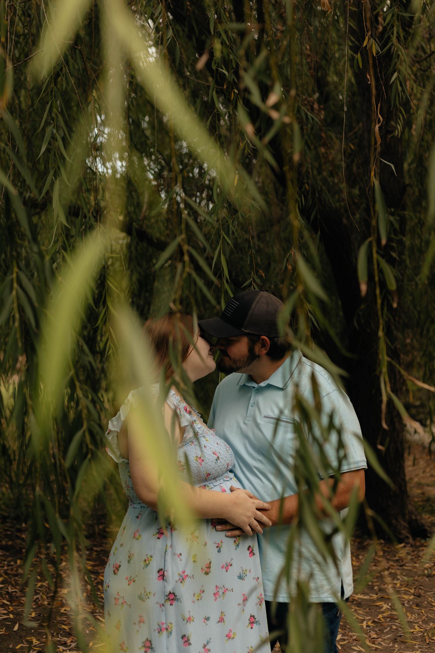A romantic photoshoot through hanging willow tree branches in natural light.