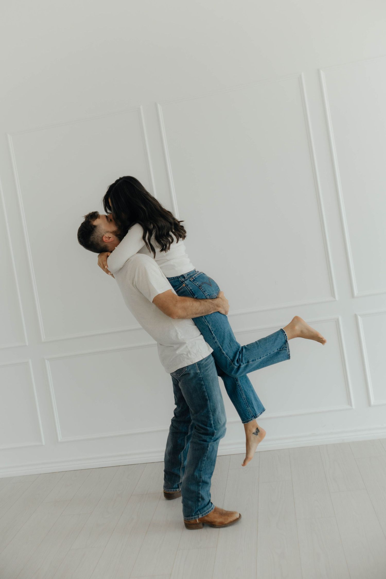 Playful couple dancing and embracing in a minimalist white room showing progressive motion.