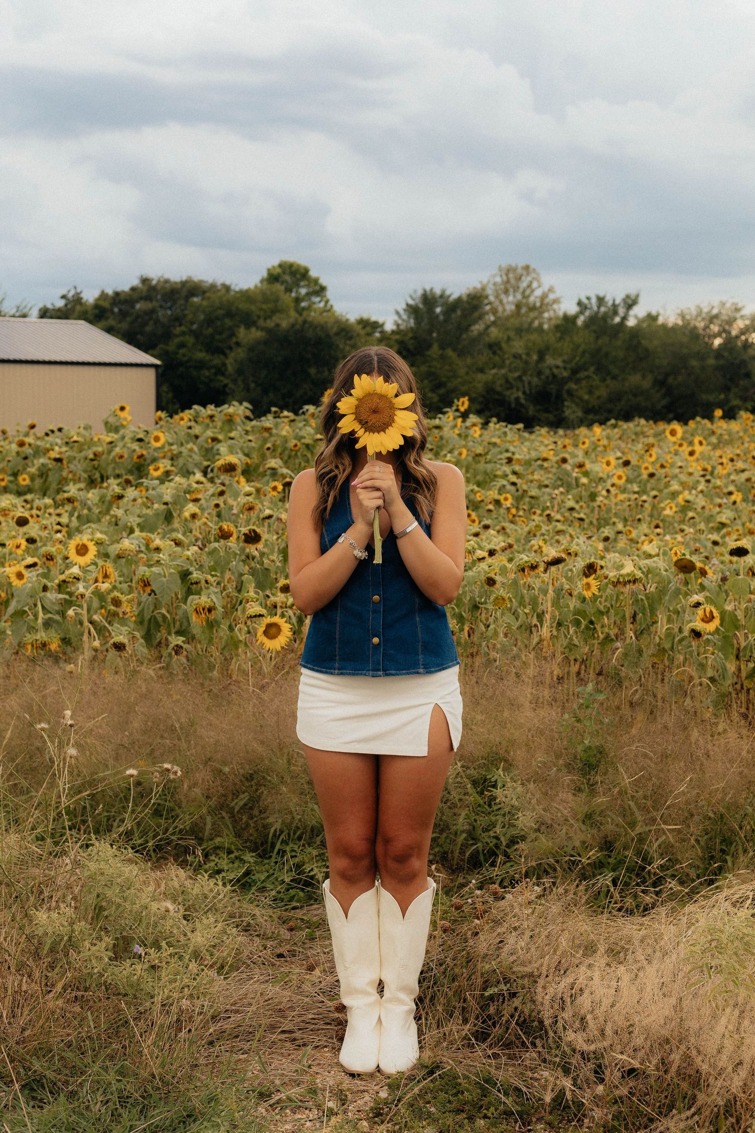 A sunflower field photoshoot featuring someone in denim and white boots.