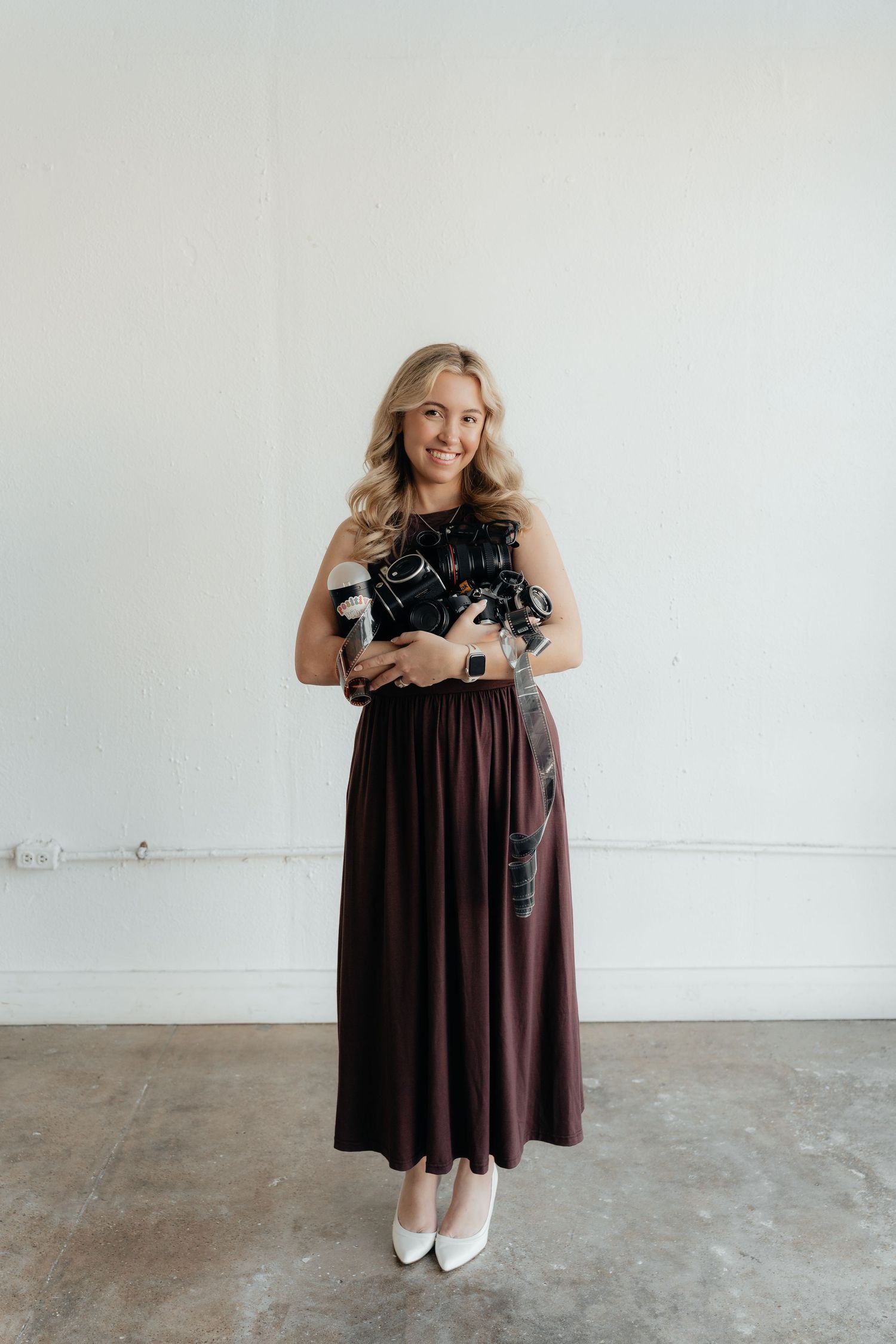 A series of photos showing someone wearing a brown dress and black shawl posing against a white wall.