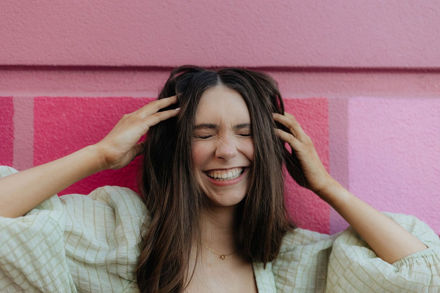 A collage of six photos showing someone in a white sweater against a pink background expressing joyful emotions.