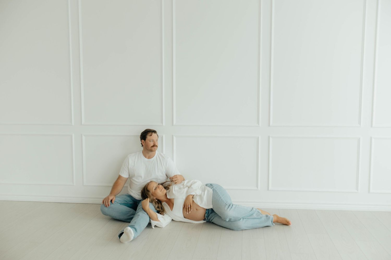 A sequence of minimalist poses against a light gray wall shows a person lounging in casual blue attire.