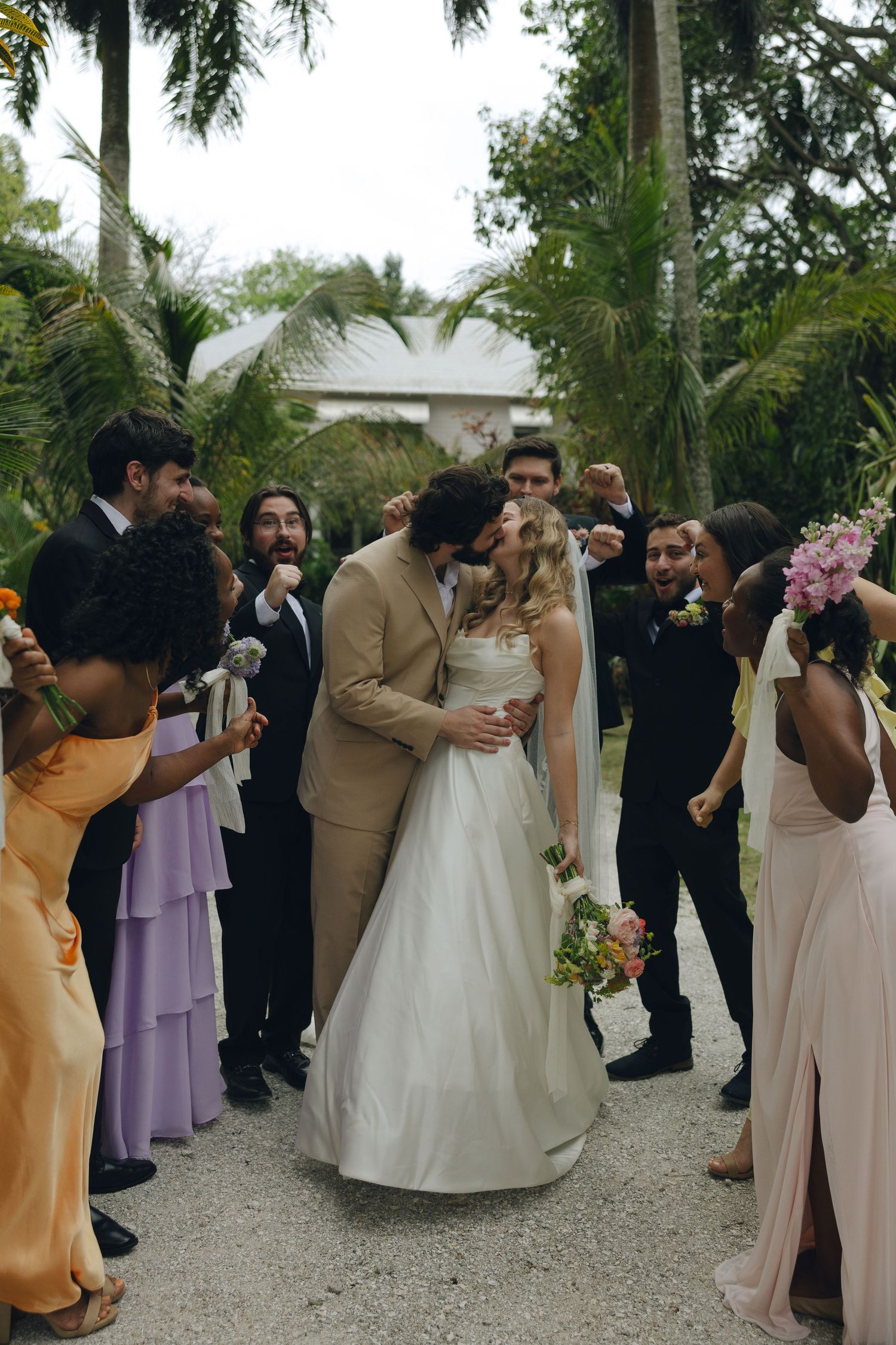 Wedding ceremony moment captured in a lush tropical garden setting with guests looking on.