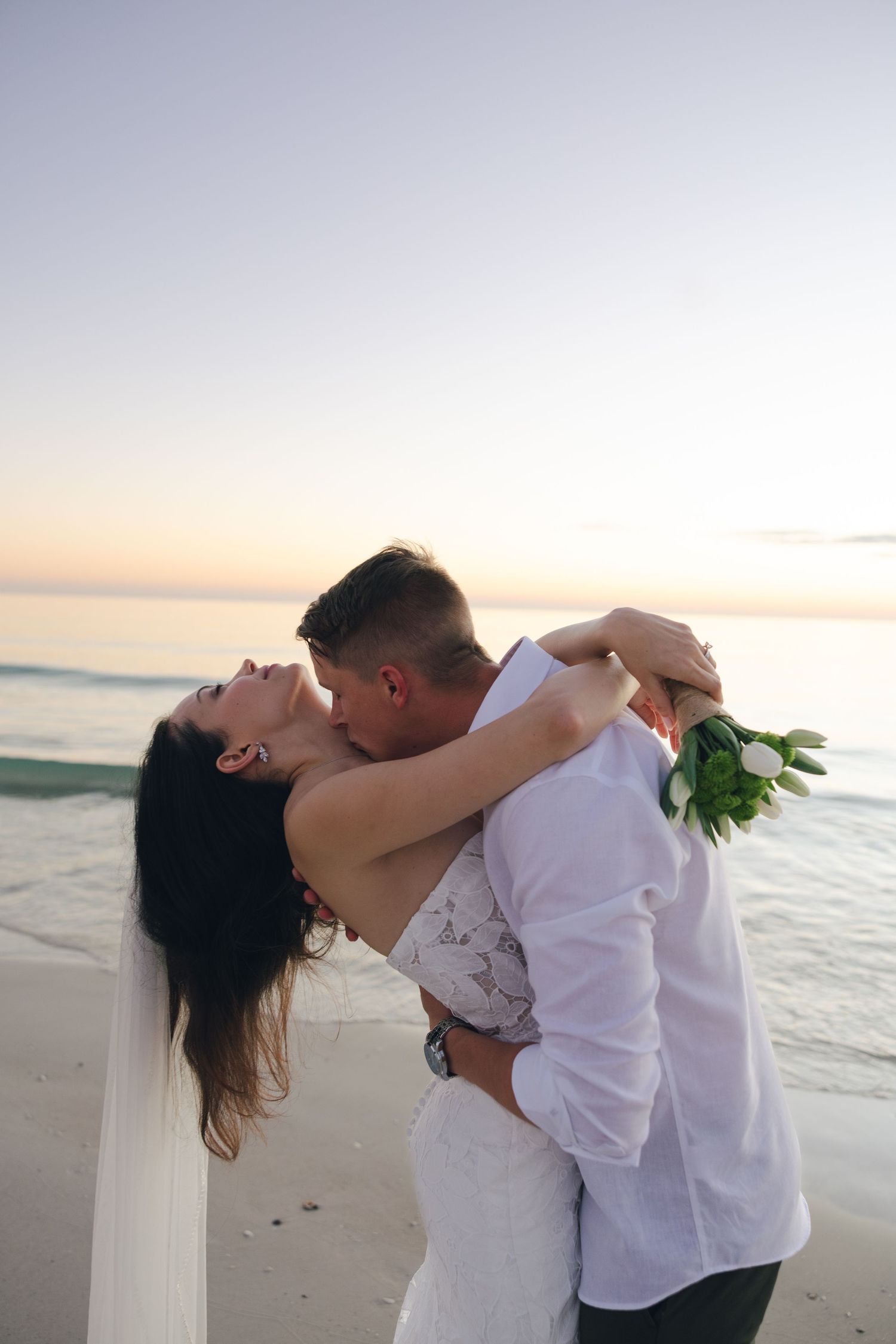 A romantic couple embraces and dances on the beach at sunset in a series of intimate poses.