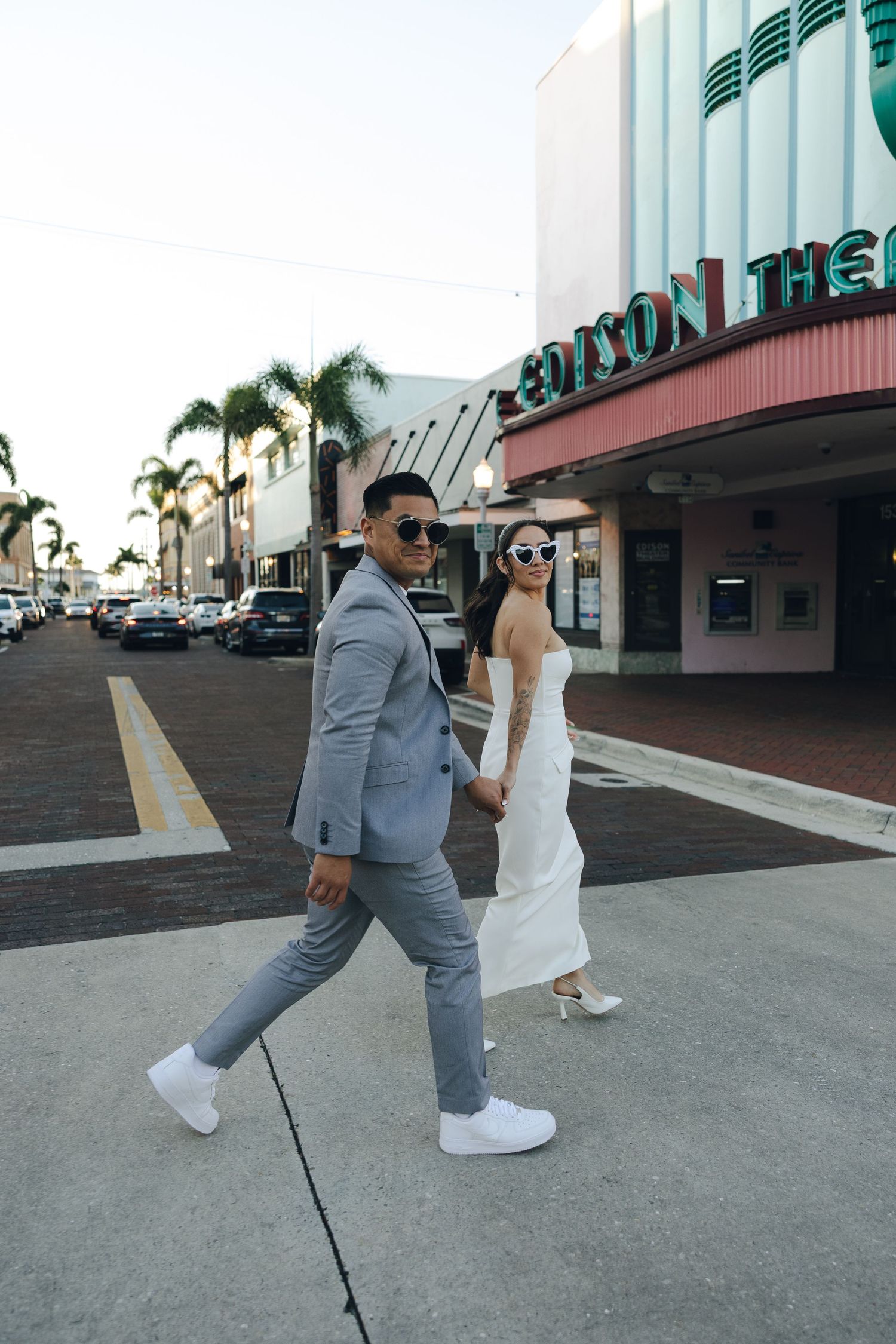 Two figures walk together on a concrete path wearing contrasting white dress and gray suit outfits in a sequence of photos.