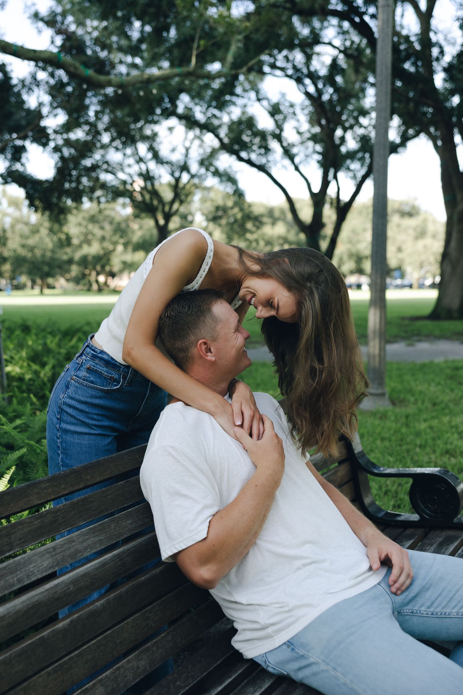 A romantic couple sharing an intimate moment while sitting together on a park bench.