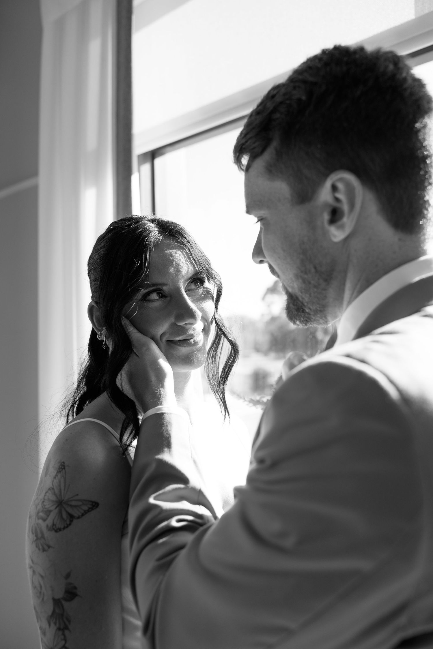 A romantic black and white photo series showing a couple in intimate moments by a window.