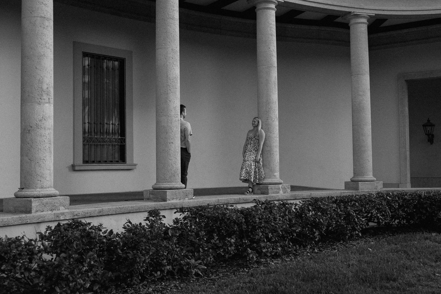 A moody black and white architectural photo featuring columns and a shadowy figure.