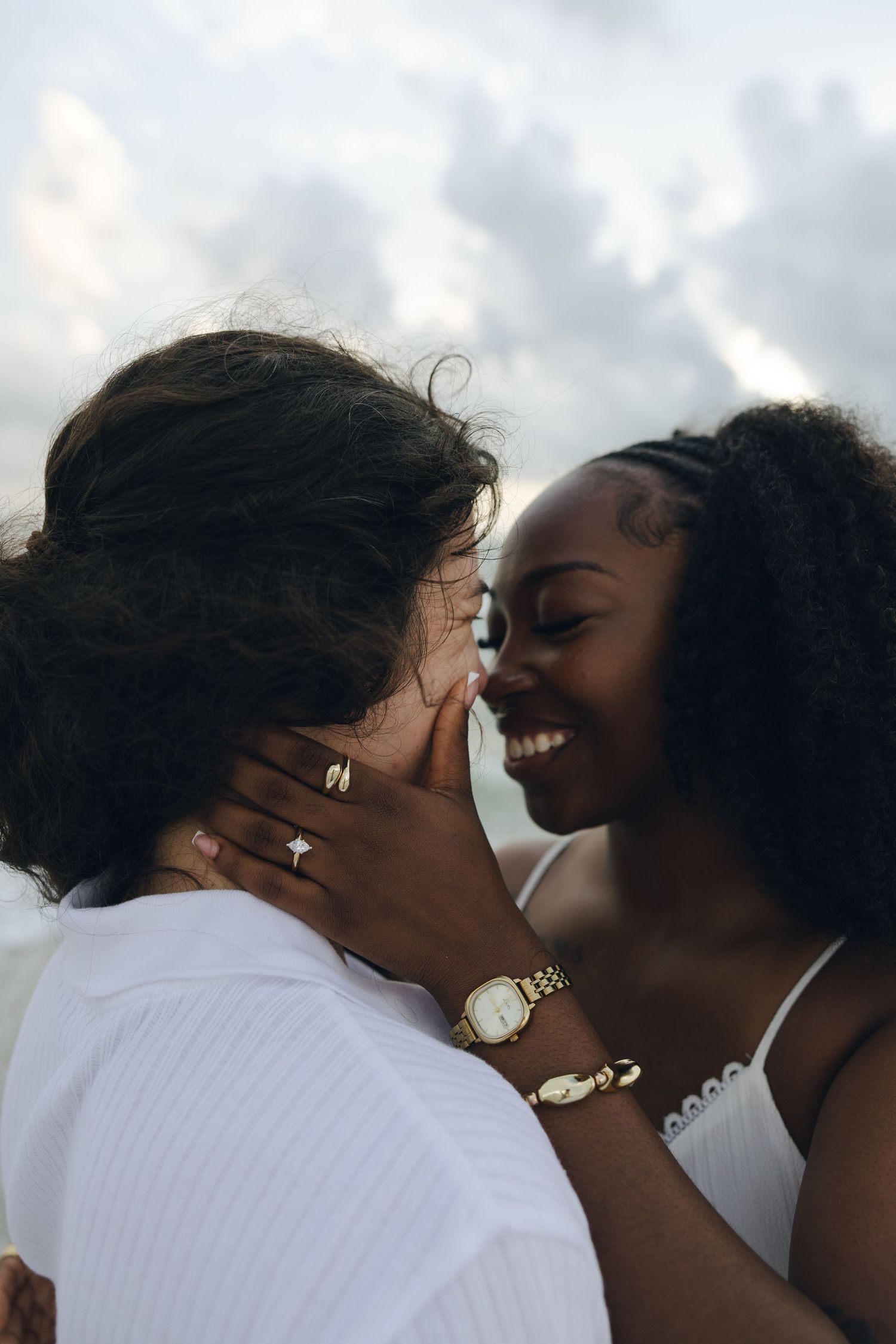 A romantic scene of a couple sharing an intimate kiss under cloudy skies.