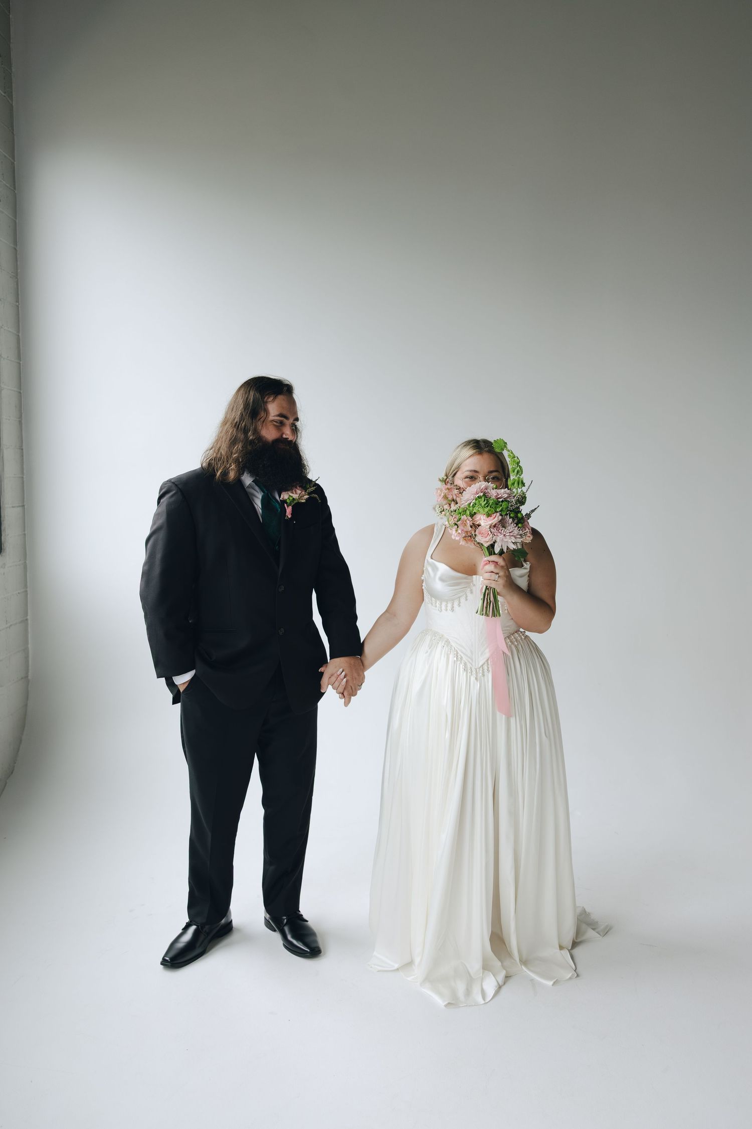 A series of minimalist wedding photos showing a couple in black and white attire against a light gray studio backdrop.