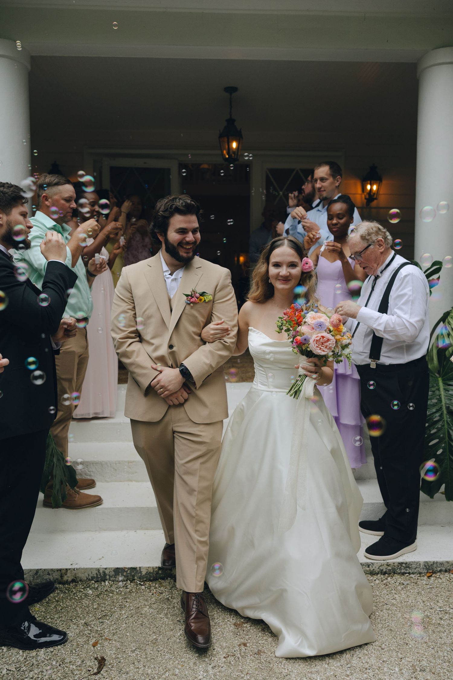 A joyful wedding ceremony exit with bubbles and guests celebrating the newlyweds.