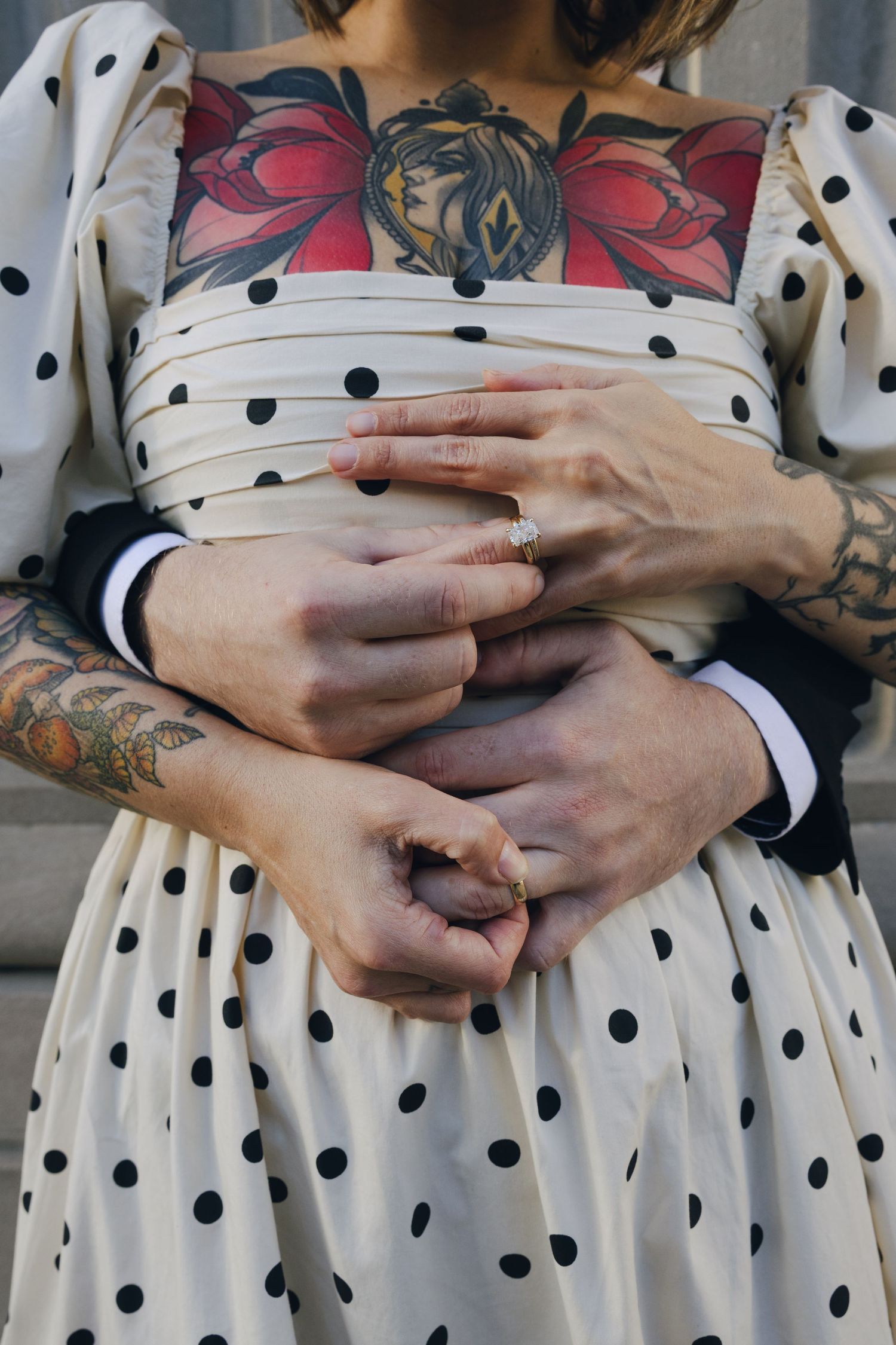 A row of bridesmaids in white polka dot dresses showing their hands with matching tattoos.