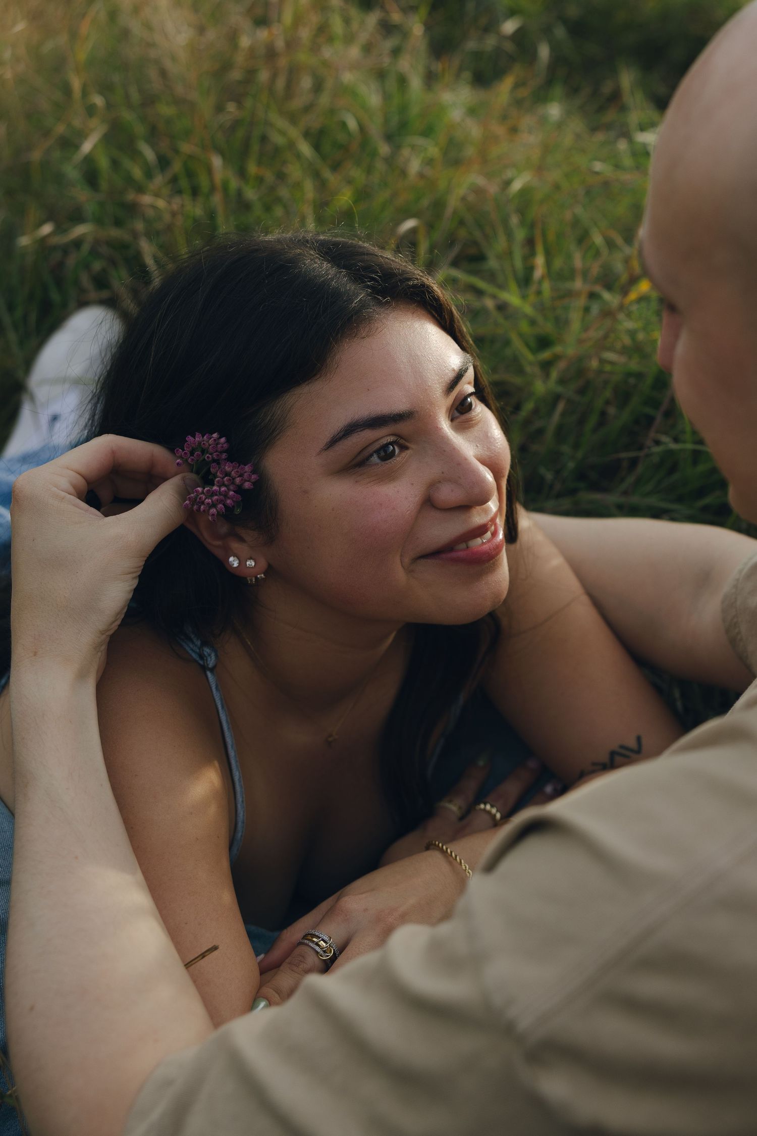 An intimate moment shared in a grassy field with flowers in her hair.