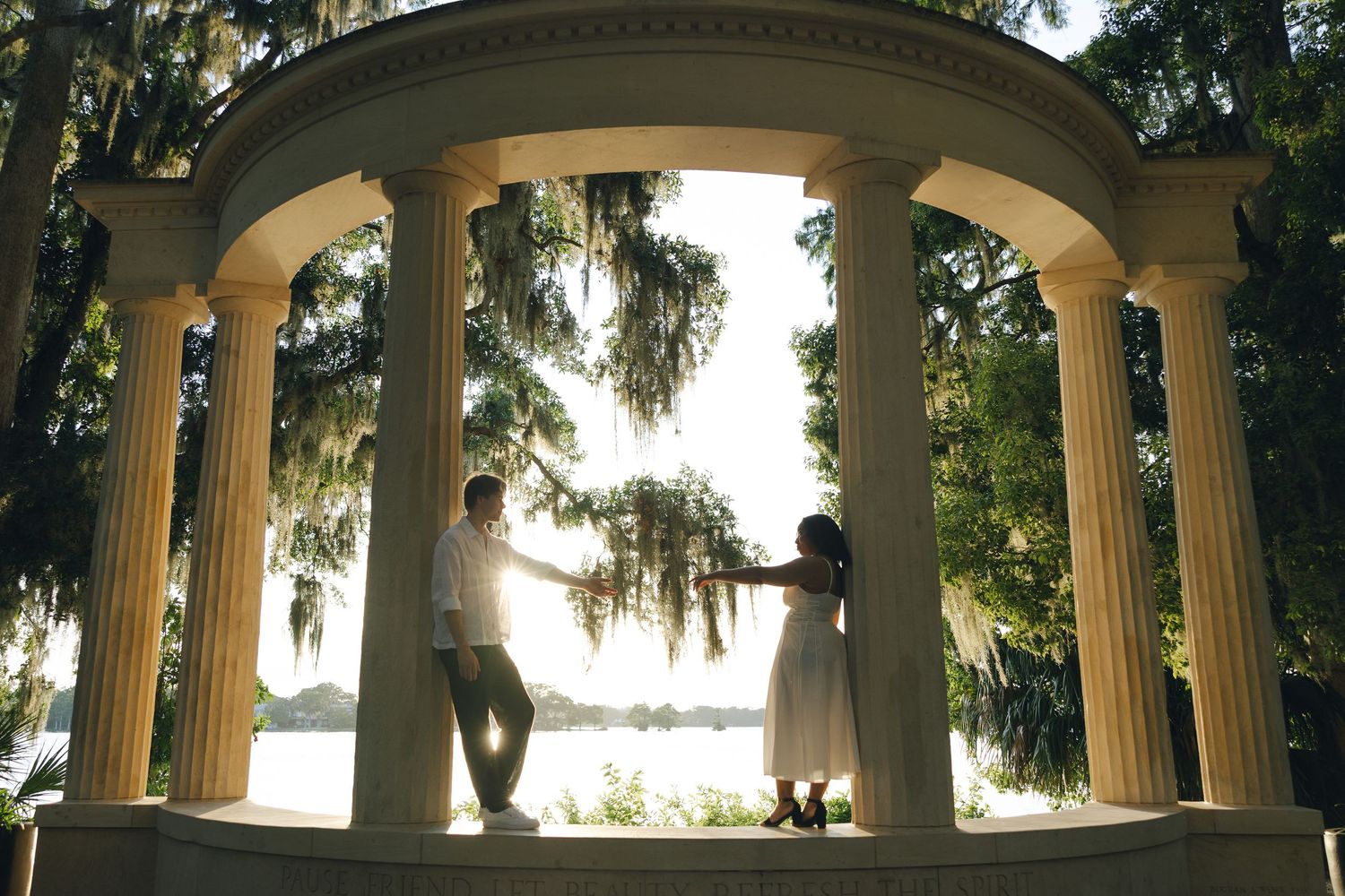 Panoramic view of a white columned gazebo structure with Spanish moss hanging from trees in the background.