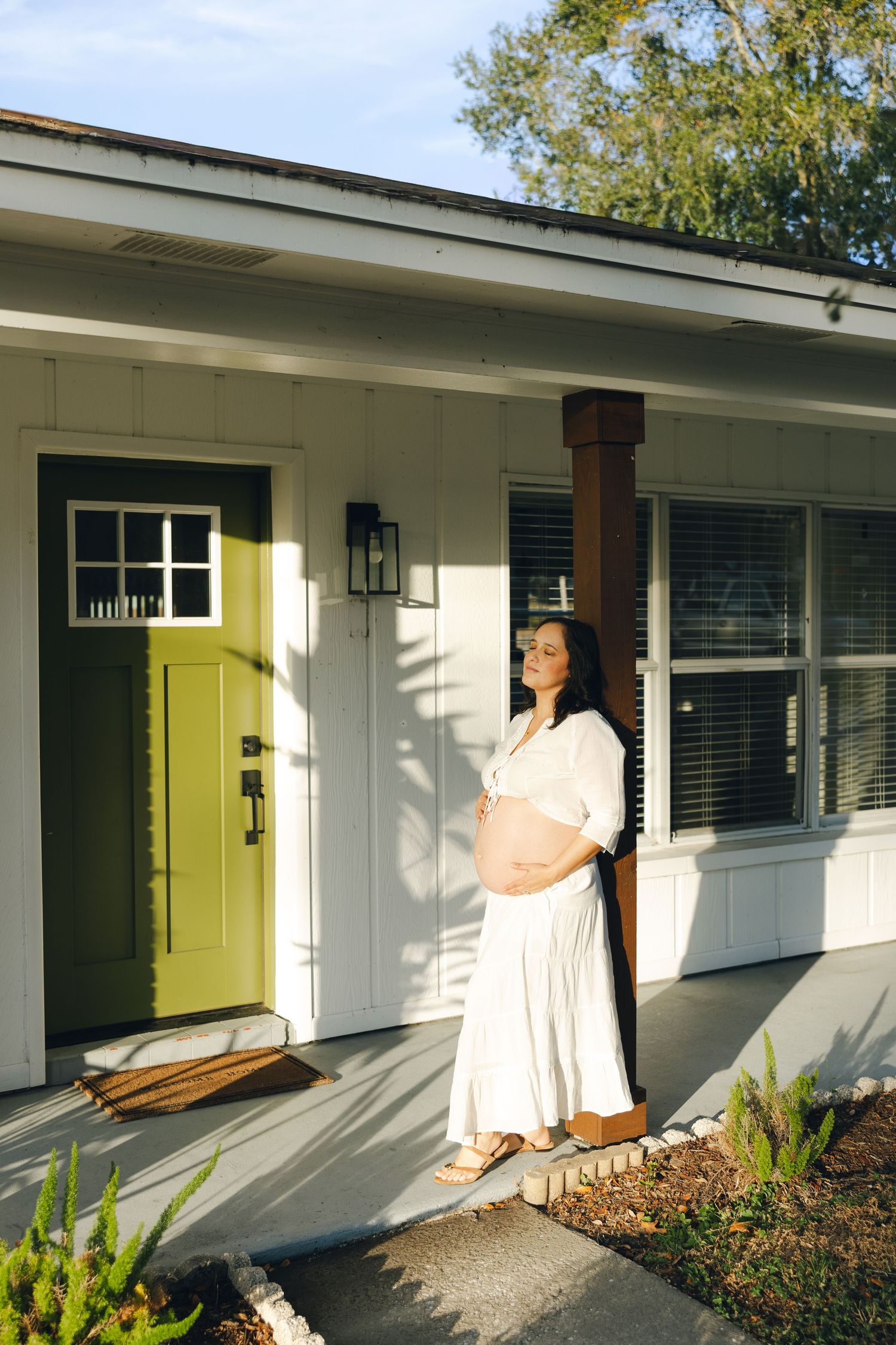 A series of five photos showing the installation process of a yellow front door on a white mid-century modern house.