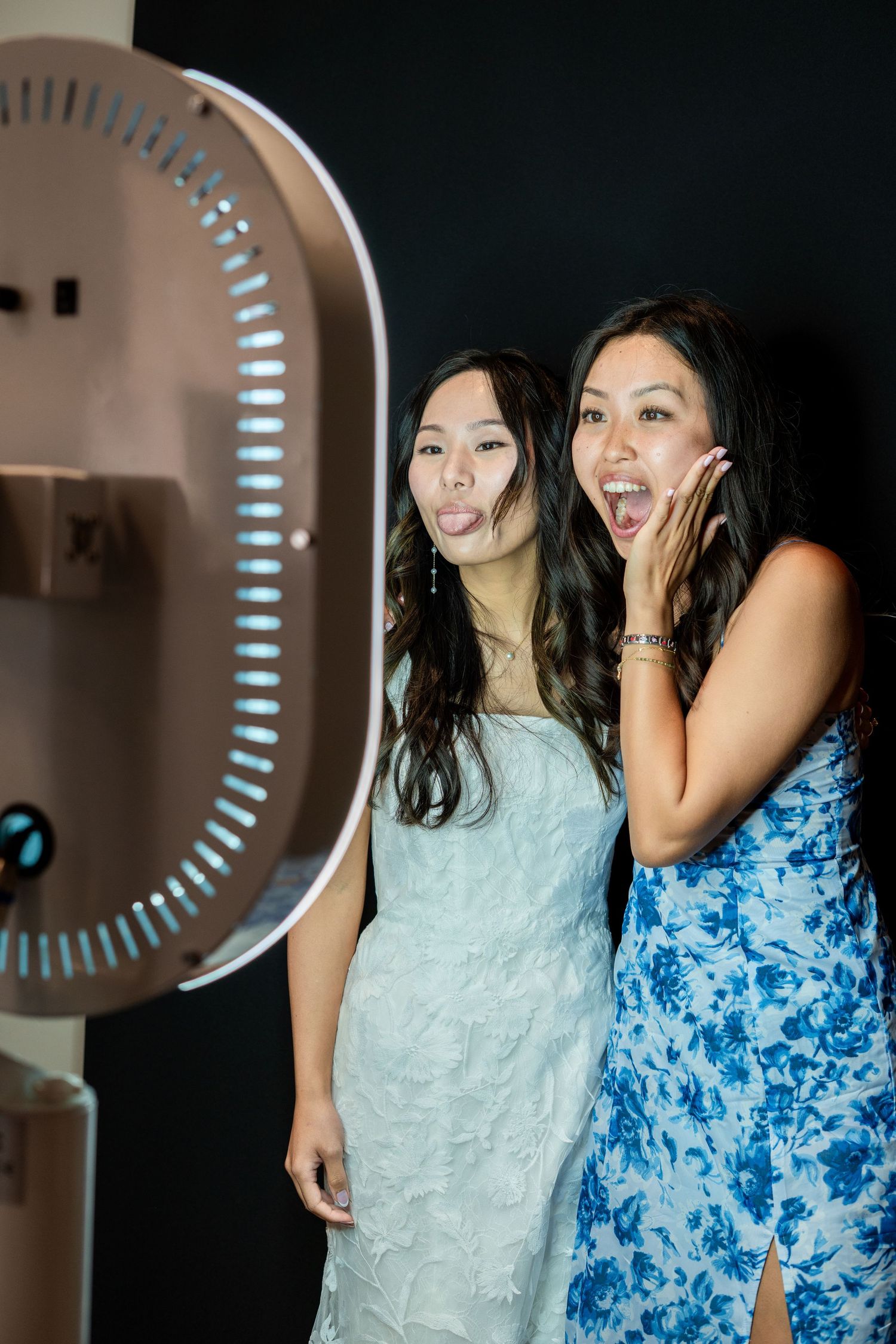Bride and wedding guest laughing together in a photo booth during the reception