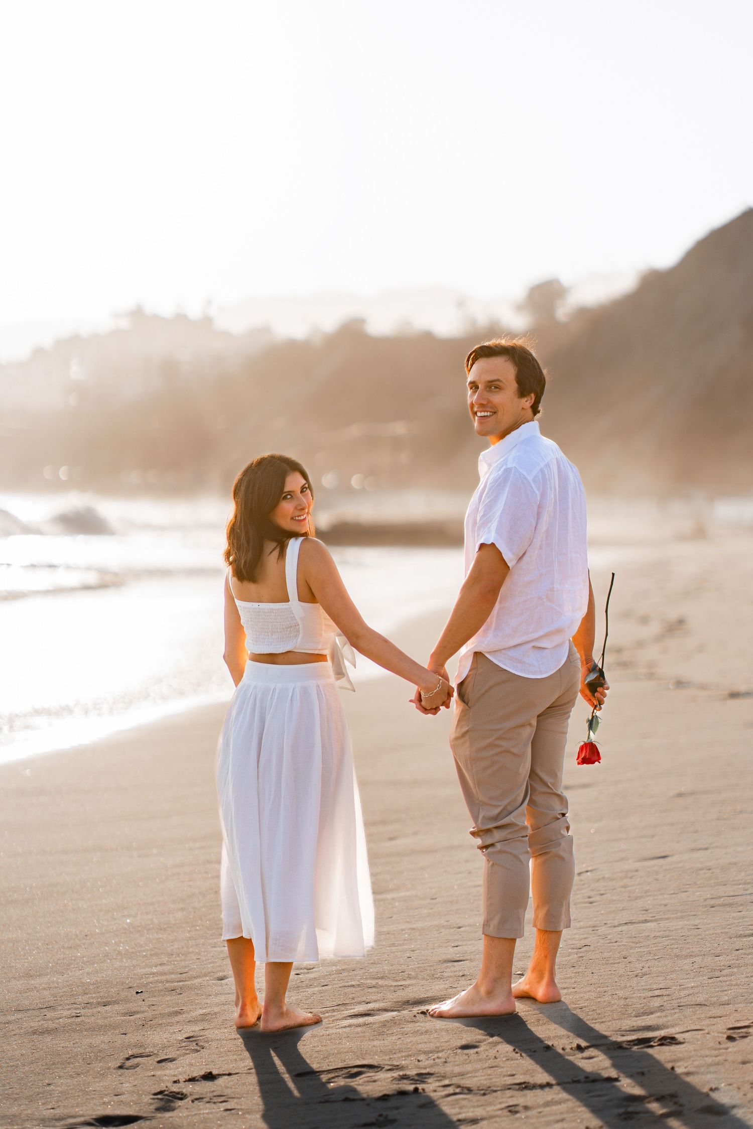 A newly engaged couple capturing romantic moments in a beautiful photoshoot by the beach.