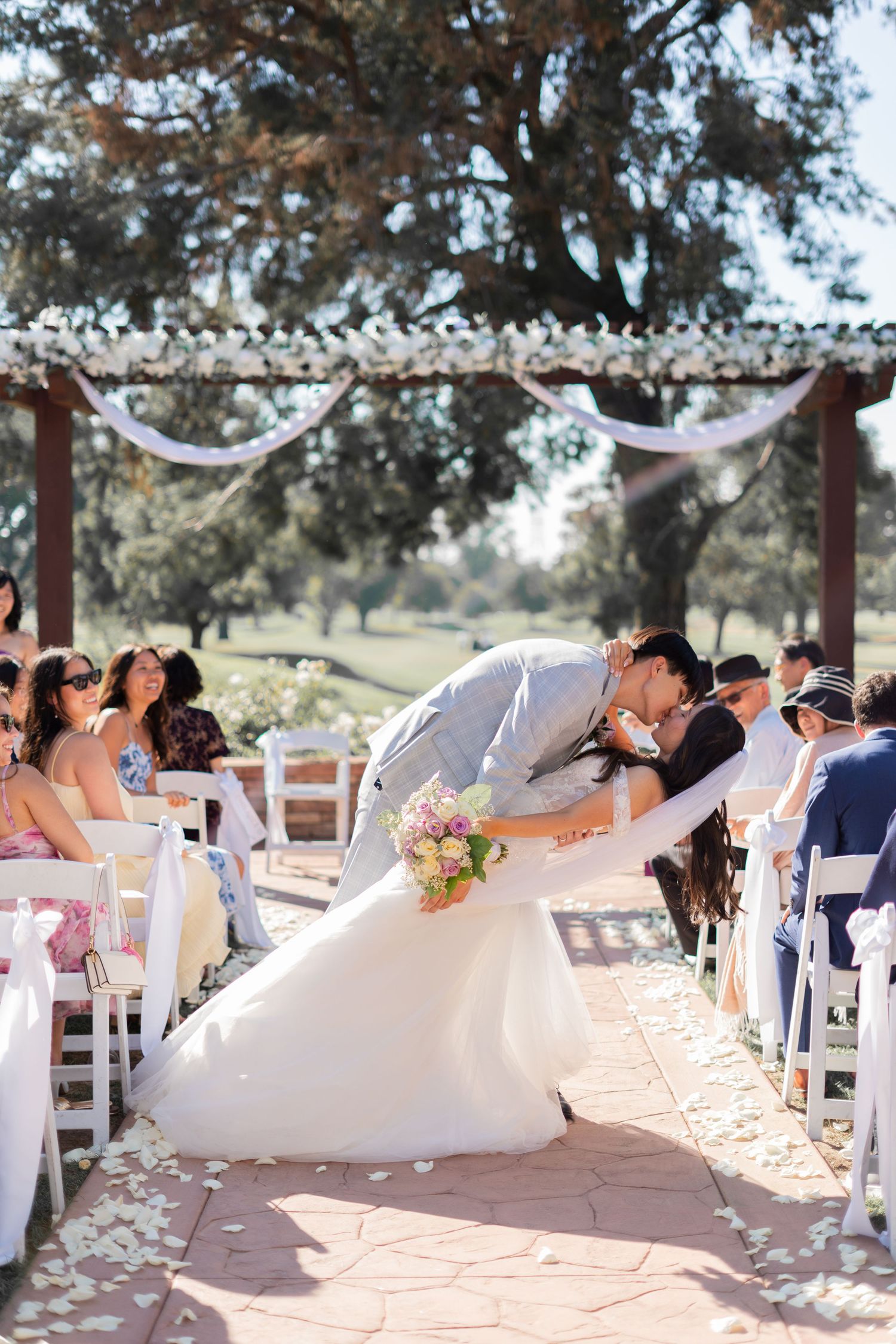 A married couple sharing a deep kiss as they make their grand exit from the wedding ceremony.