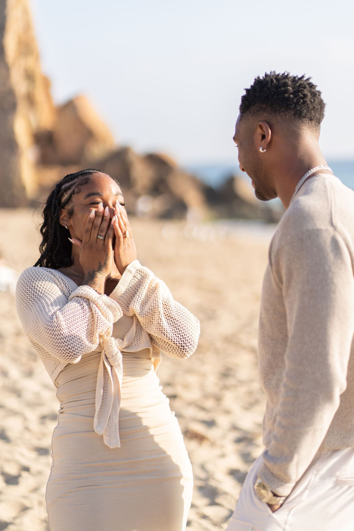 Romantic couple enjoying their engagement at Point Dume Beach, capturing love, ocean views, and golden California coastal vibes.