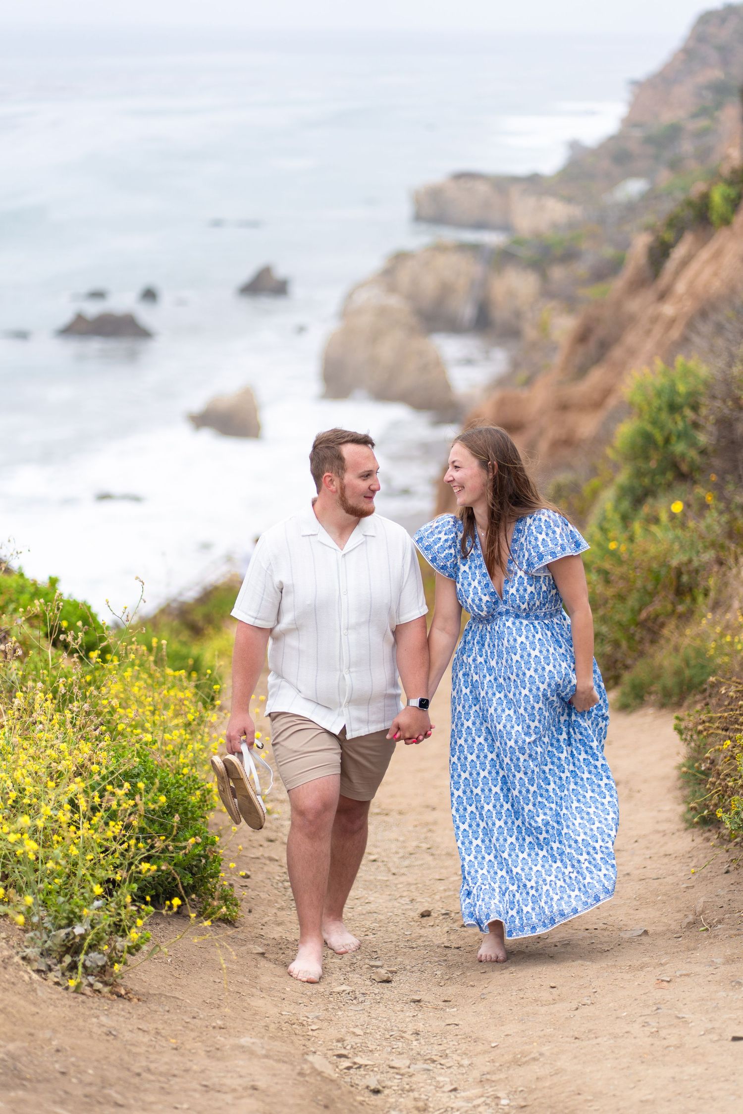 Newly engaged couple walking hand-in-hand up the scenic path at El Matador Beach—love’s journey begins. #ElMatadorBeach #JustEngaged #Romant