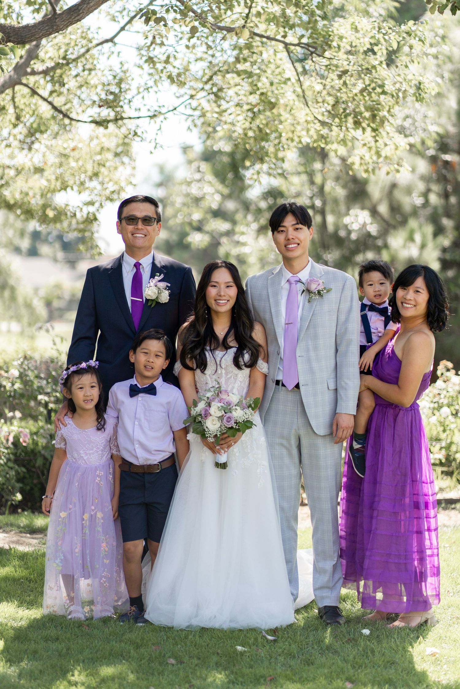 Bride and groom capturing cherished family photos surrounded by their loving relatives.