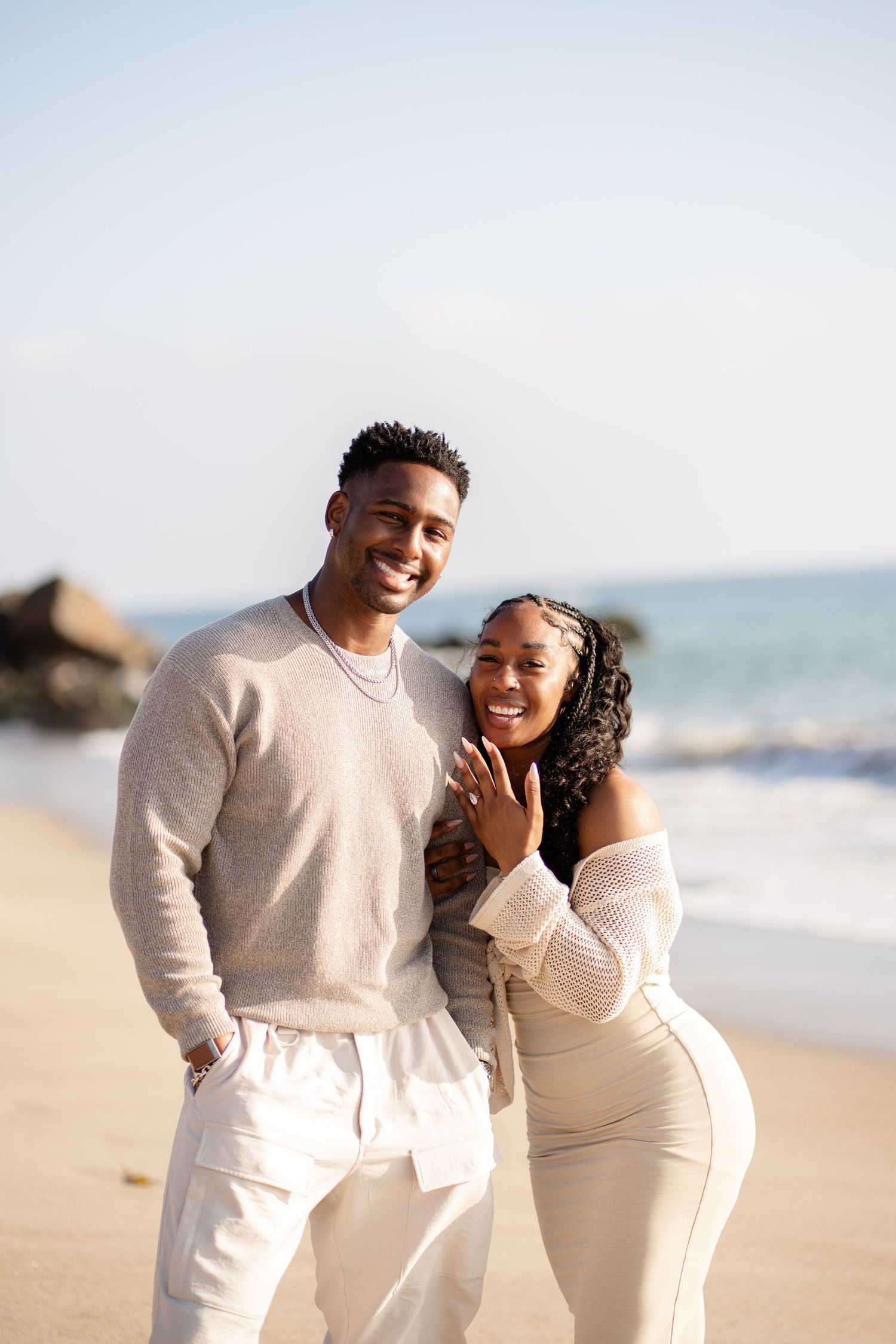 Romantic couple enjoying their engagement at Point Dume Beach, capturing love, ocean views, and golden California coastal vibes.