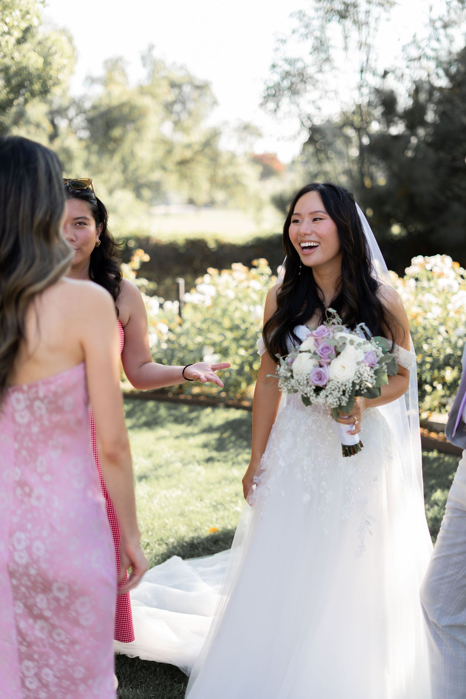 Bride sharing a joyful moment and quick conversation with friends on her wedding day.