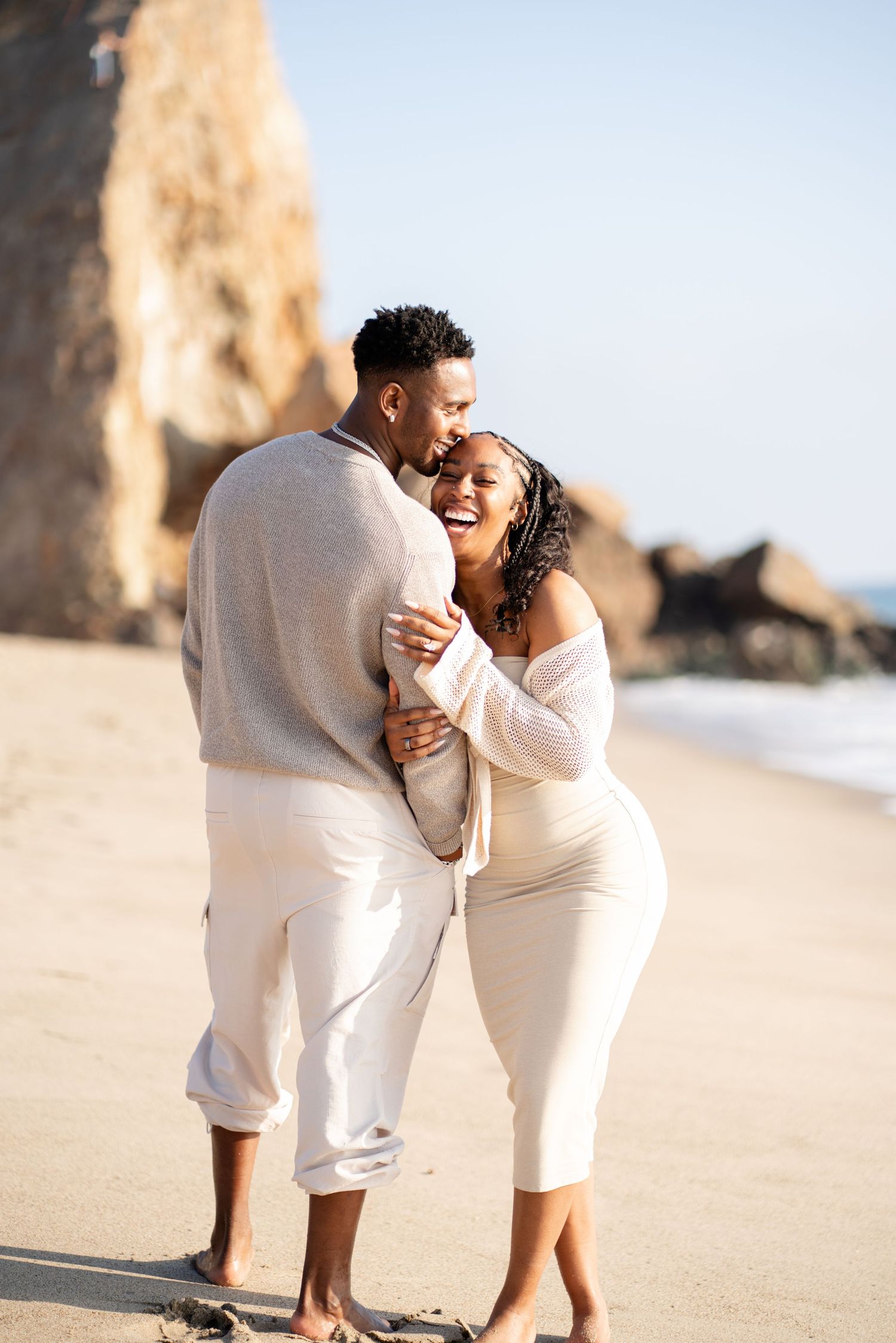 Romantic couple enjoying their engagement at Point Dume Beach, capturing love, ocean views, and golden California coastal vibes.