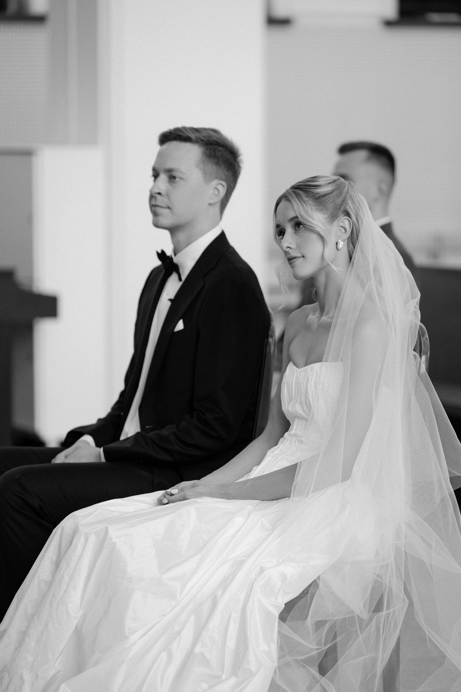 Black and white portrait of a bride and groom seated together during their church wedding ceremony.