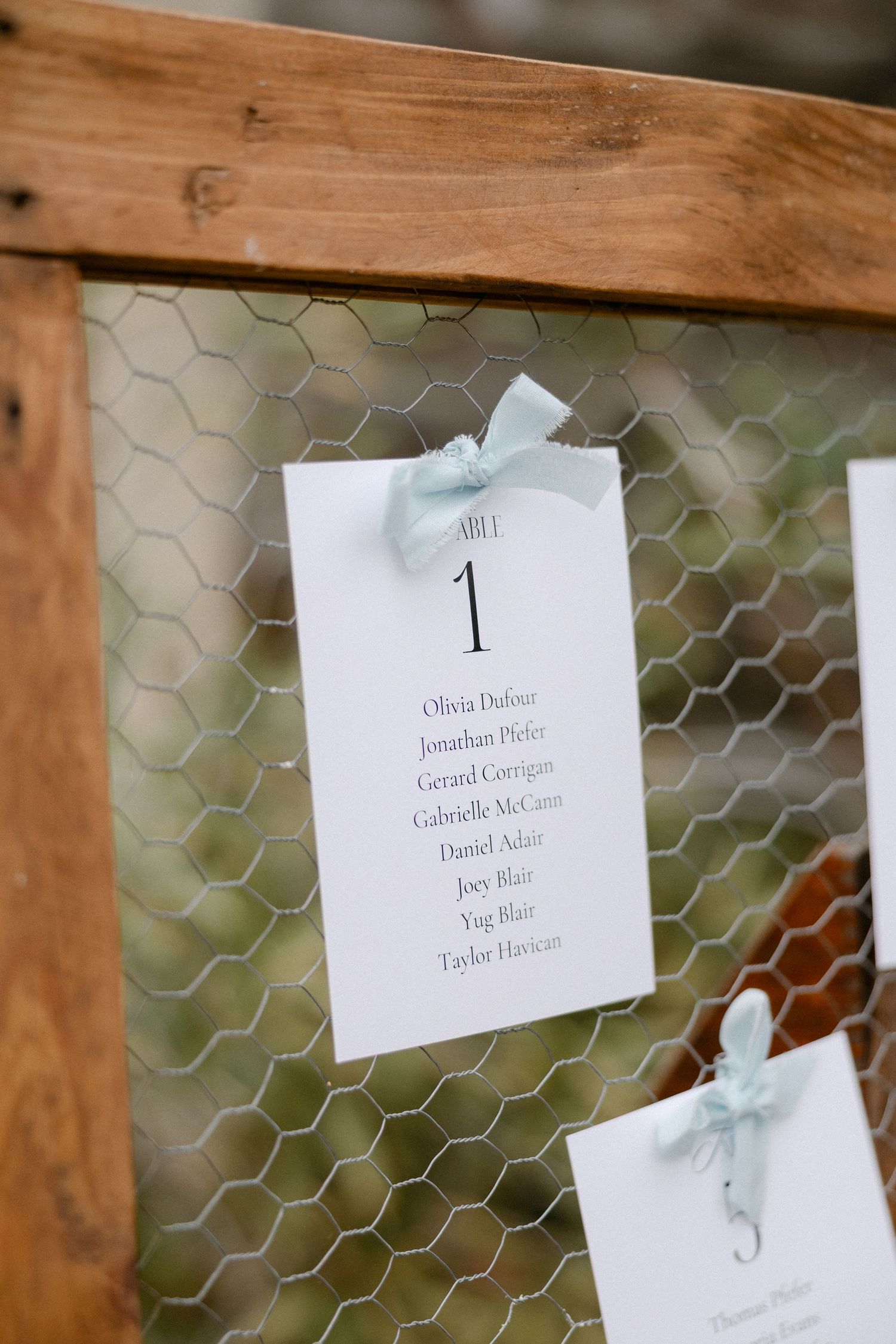 Wedding seating chart card for Table 1 attached to rustic wooden frame with chicken wire.