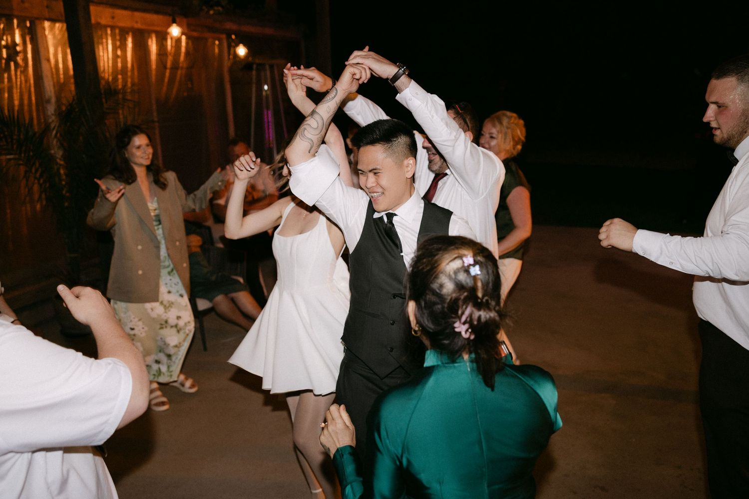 Energetic wedding reception dance floor with guests forming a circle and dancing joyfully together.