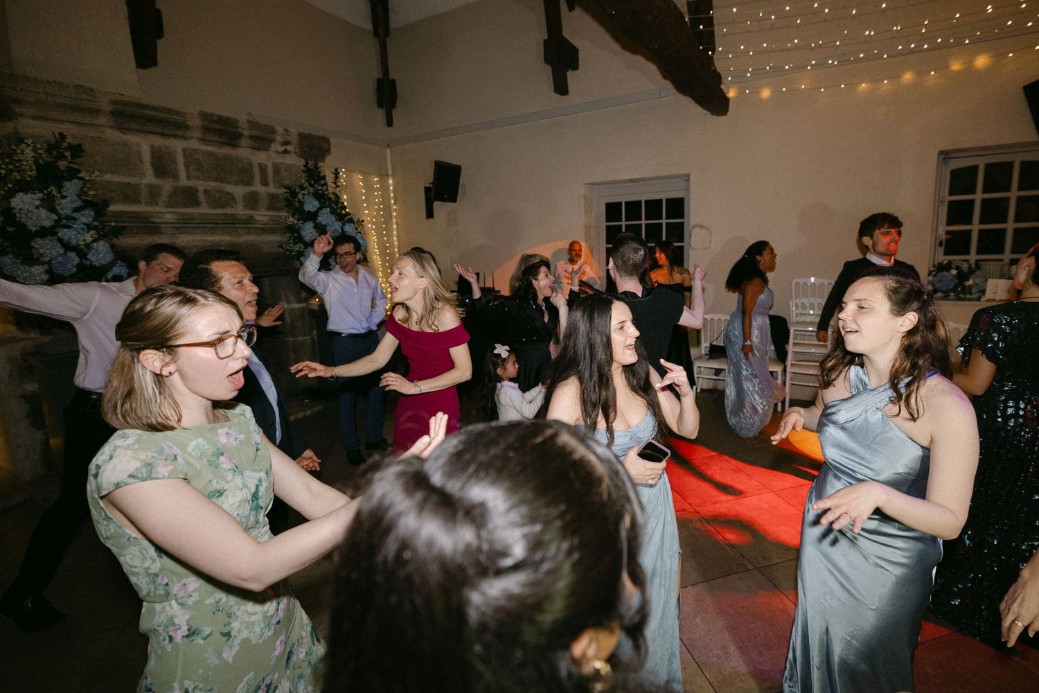 Guests dancing and celebrating on a decorated dance floor during a lively evening wedding reception.