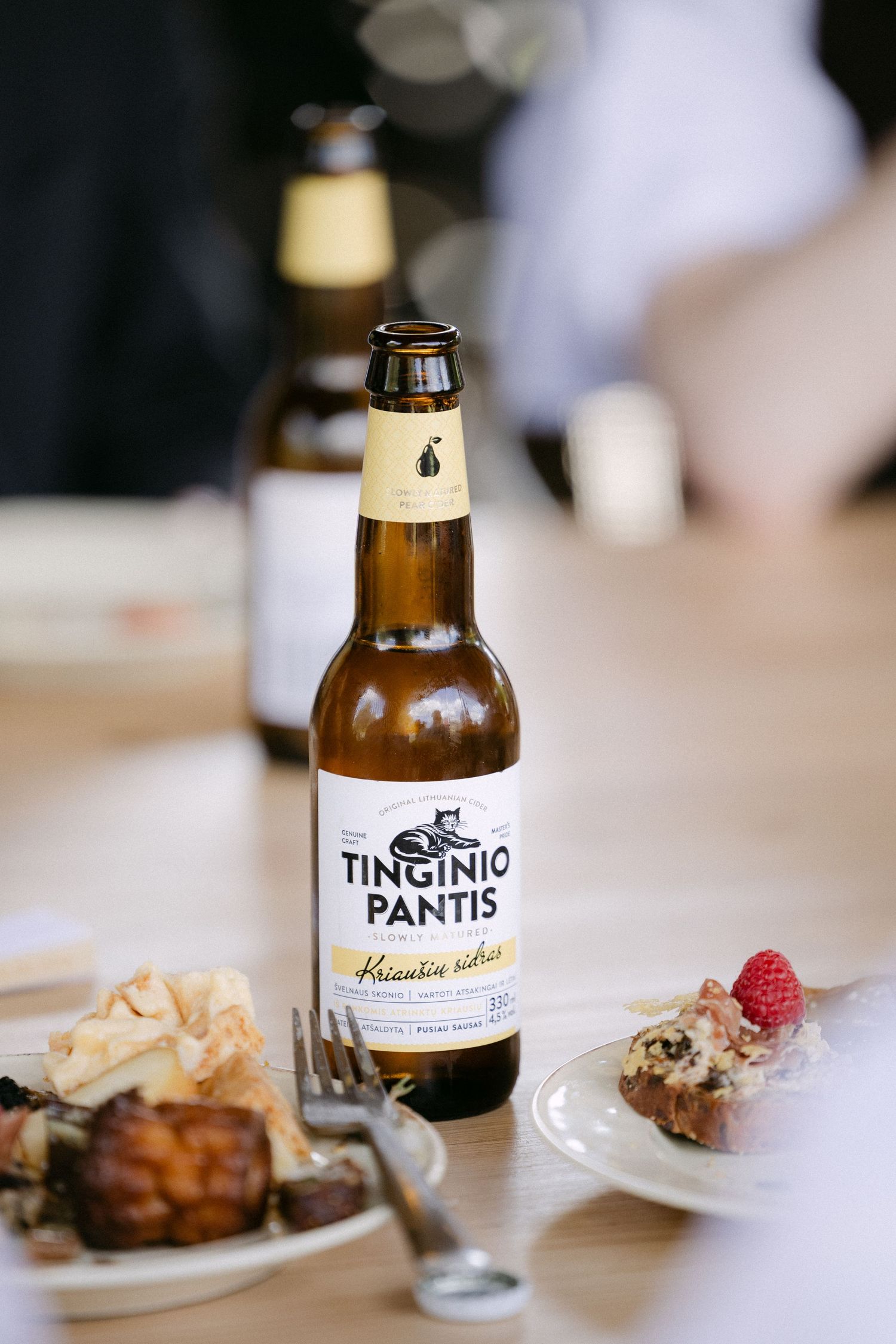 Bottle of Tinginio Pantis beer on a wooden table beside plates of food at a wedding reception.