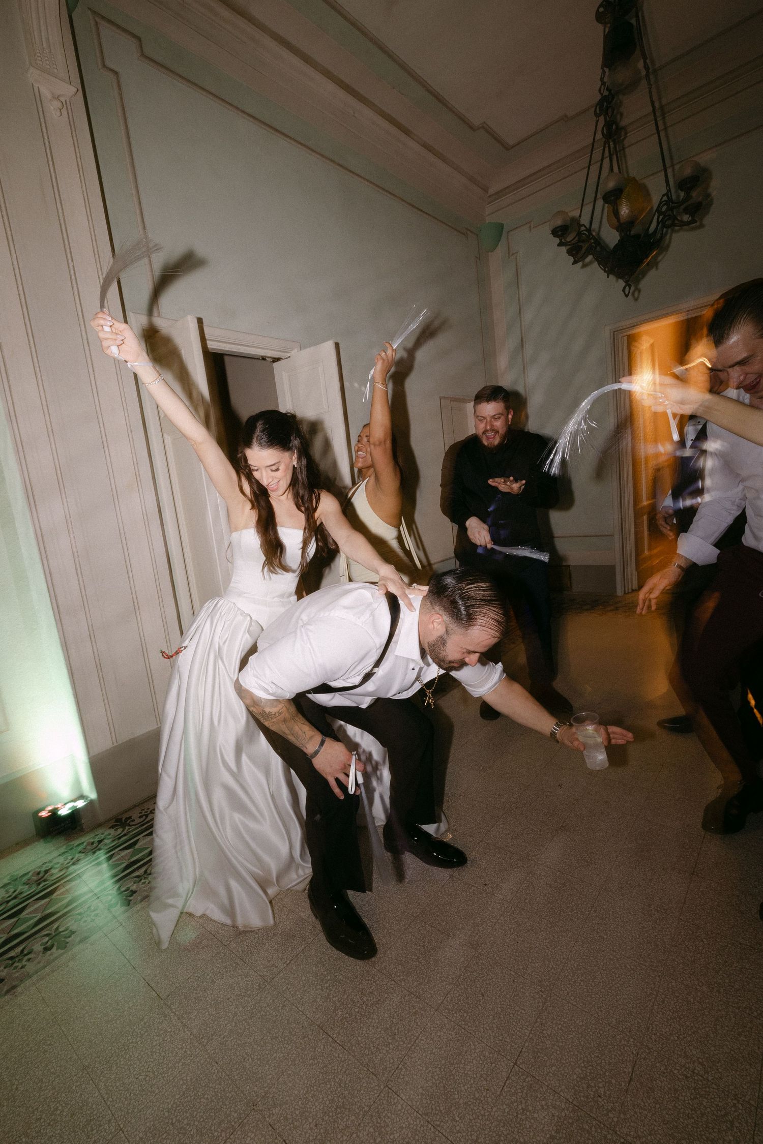 Bride and groom perform dramatic dance dip with guests watching at wedding reception celebration.