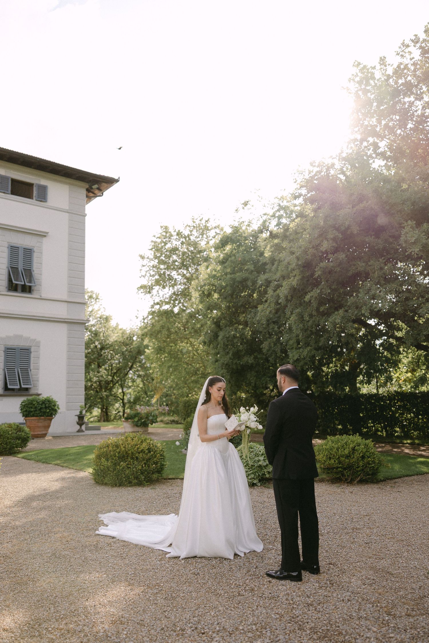Bride and groom share a romantic first look moment outside an elegant Italian villa surrounded by lush gardens.