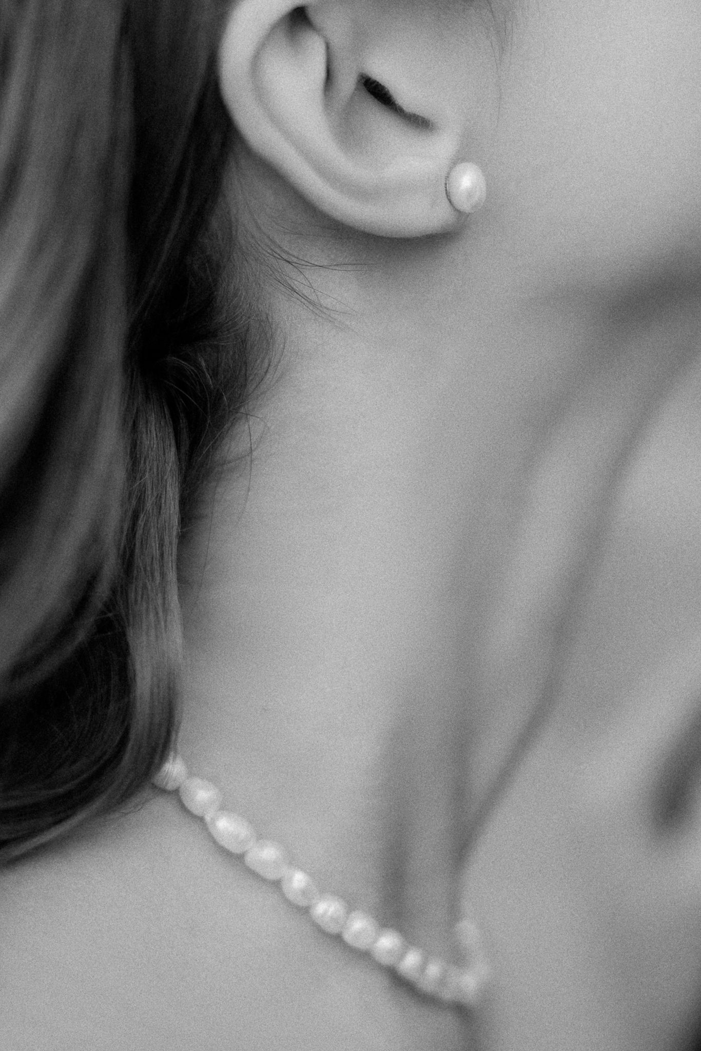 Close up black and white photo of pearl earring and necklace jewelry.