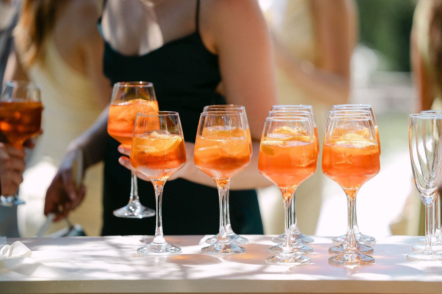 Elegant Aperol Spritz cocktails in wine glasses lined up at a wedding reception bar.