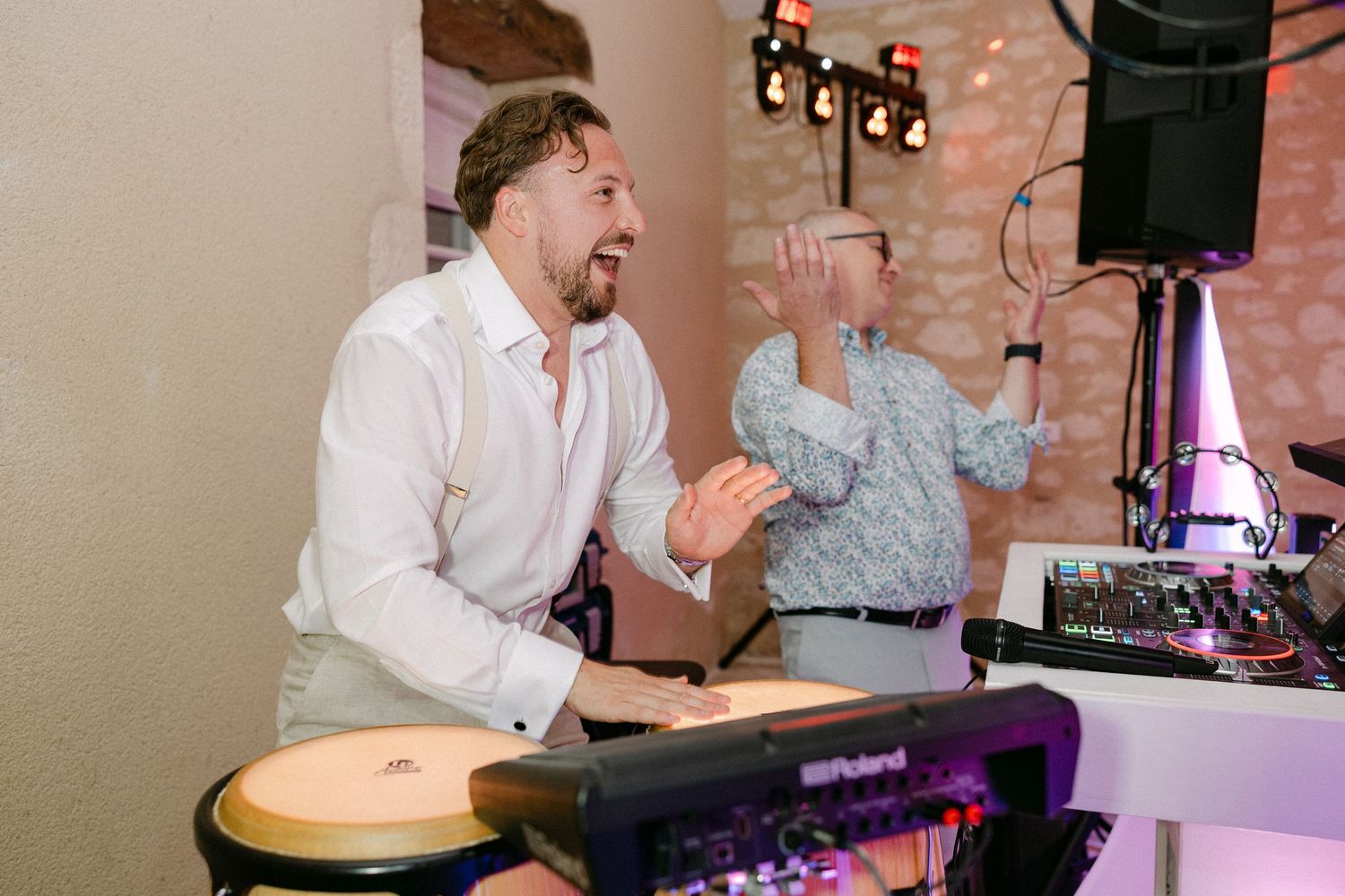 Energetic musician playing bongo drums at a lively wedding reception with DJ equipment nearby.