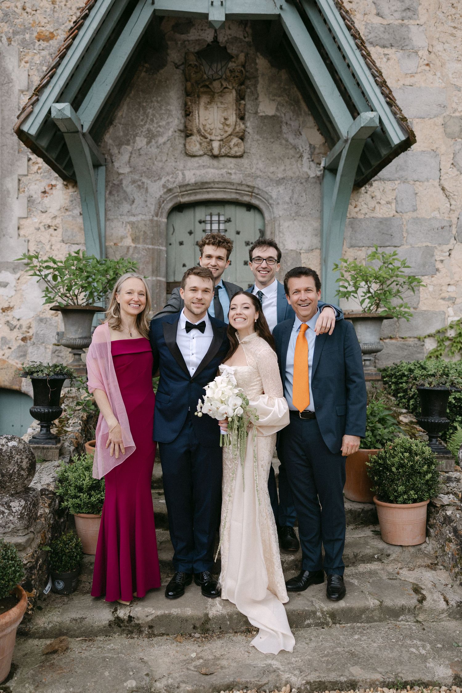 Wedding party posing on stone steps outside historic venue with bride holding bouquet.