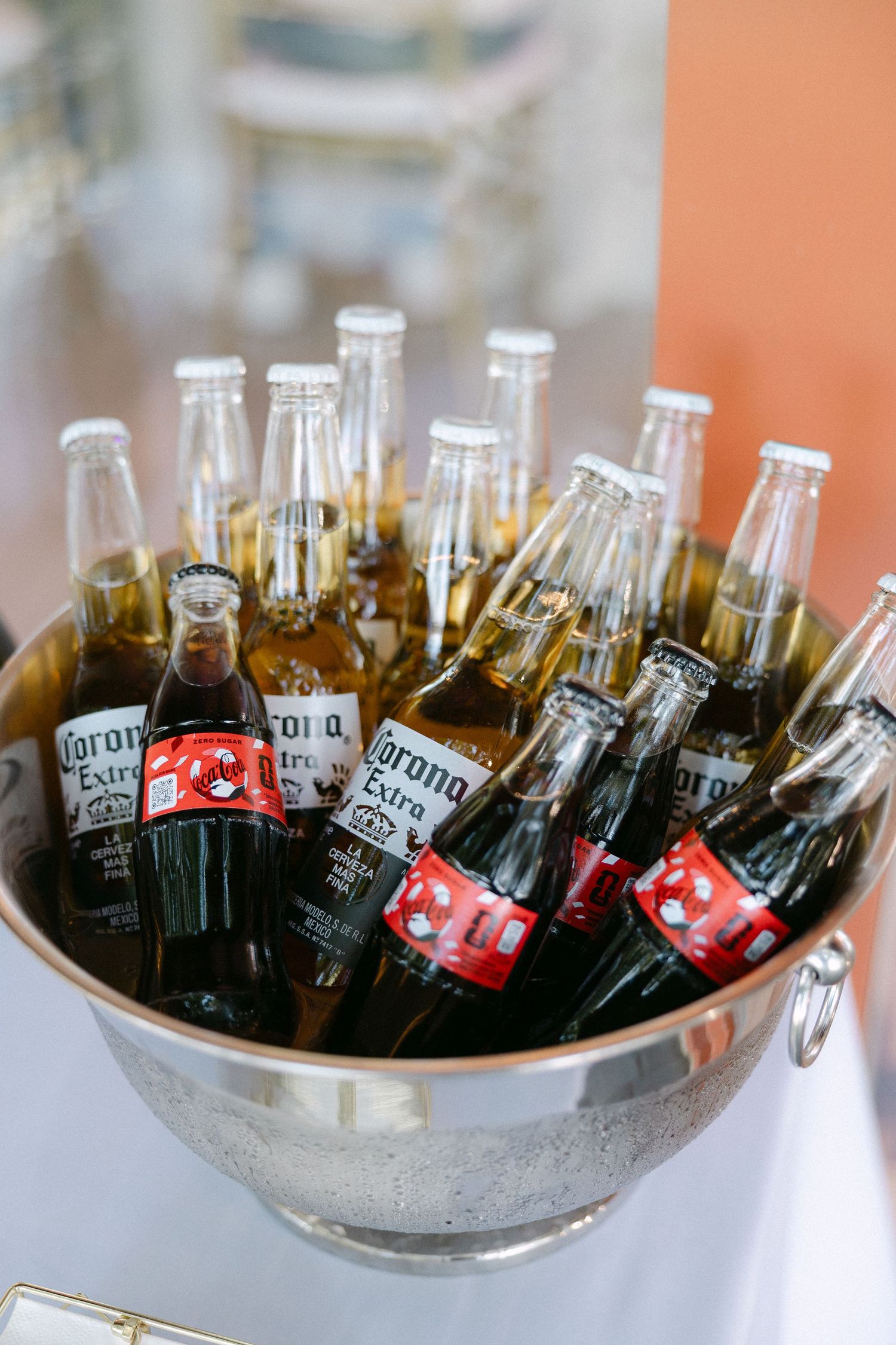 Bucket of Corona Extra beer and Coca-Cola bottles chilling at wedding reception bar.
