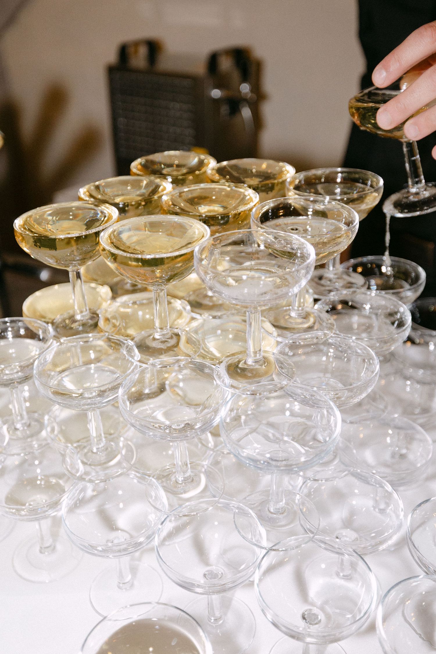 Elegant champagne coupe glasses arranged in pyramid display at wedding reception bar.