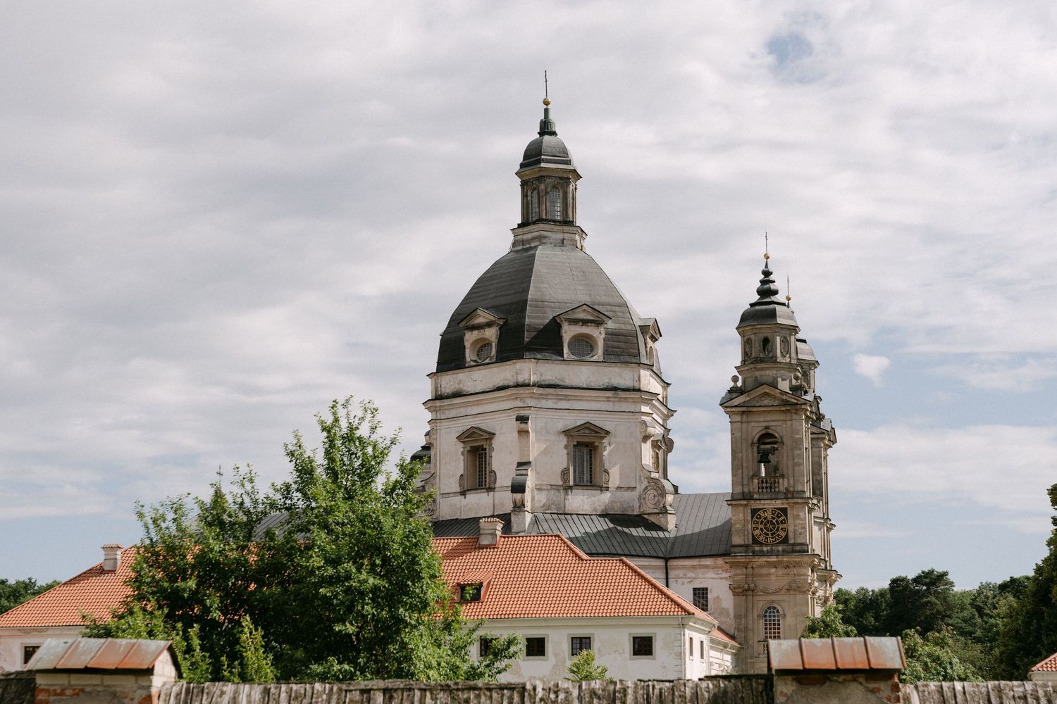 Historic baroque church with a large dome and bell tower under a cloudy sky.