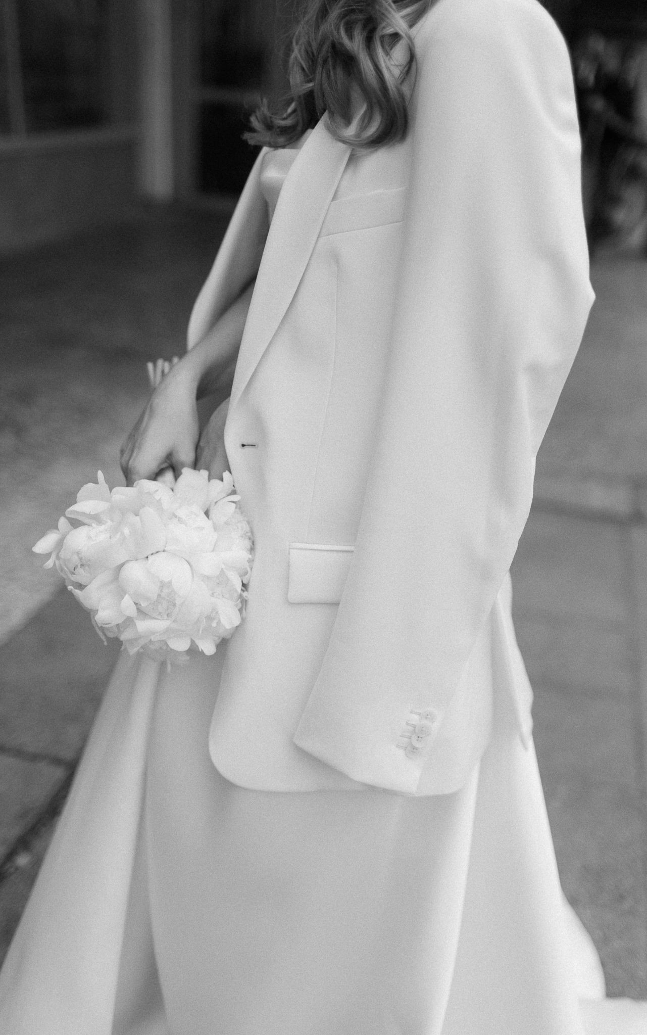 Close up of classic white bridal attire with delicate floral bouquet.