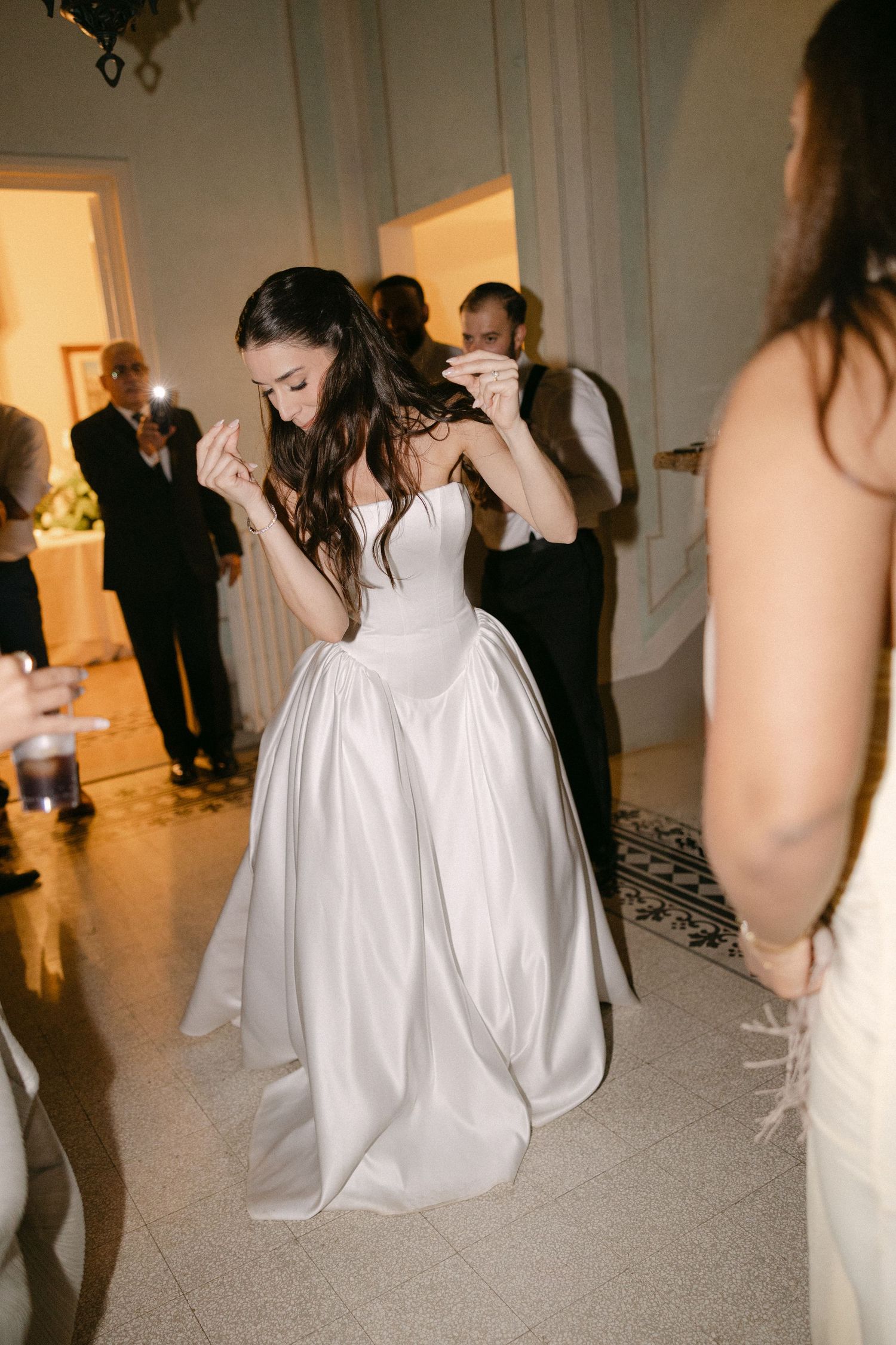 Bride in strapless white ballgown dancing joyfully on the dance floor at her wedding reception.