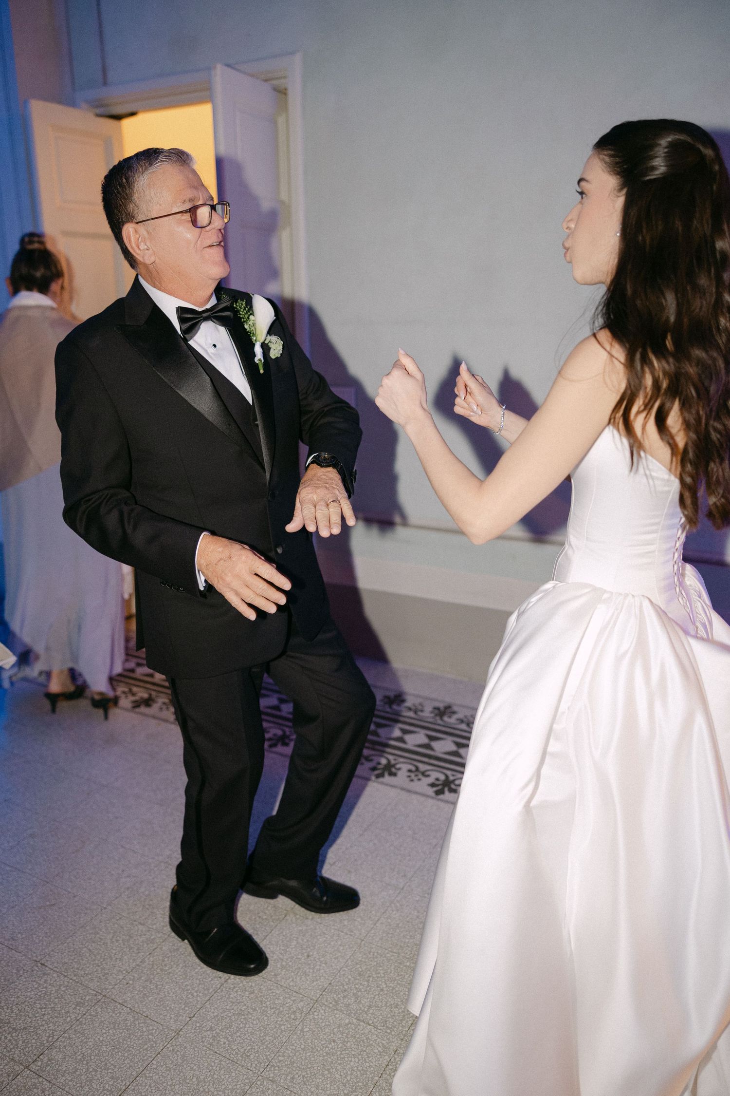 Bride in white strapless gown shares joyful father-daughter dance at elegant wedding reception.
