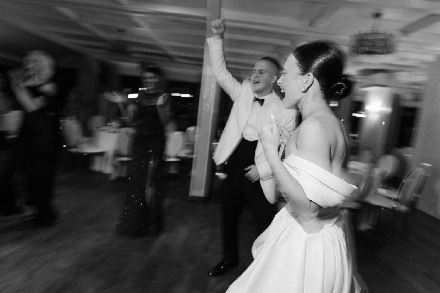 Bride and groom sharing joyful first dance in black and white photo at elegant wedding reception.