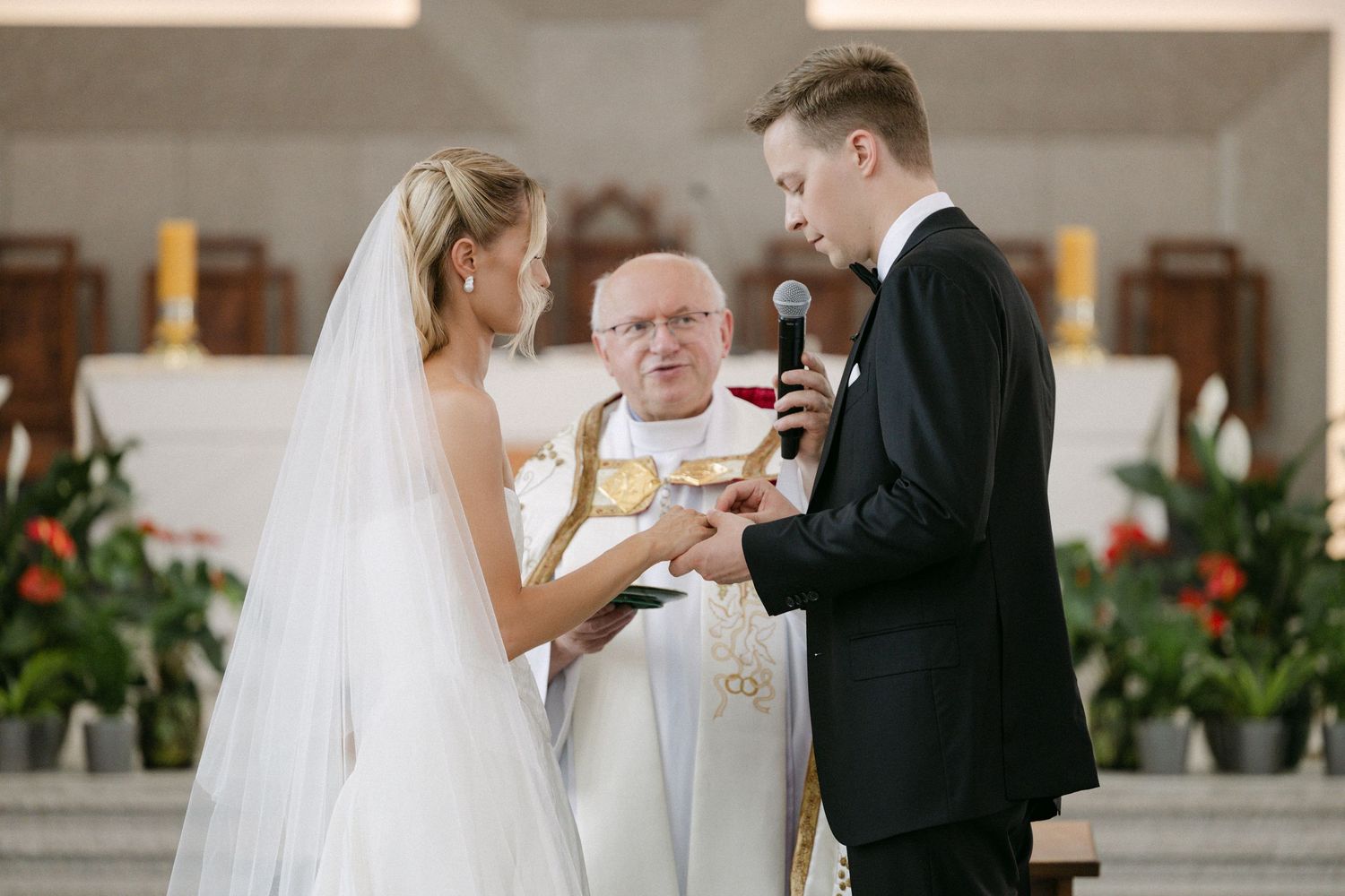 Bride and groom exchange vows at the altar with an officiant during a church wedding ceremony.