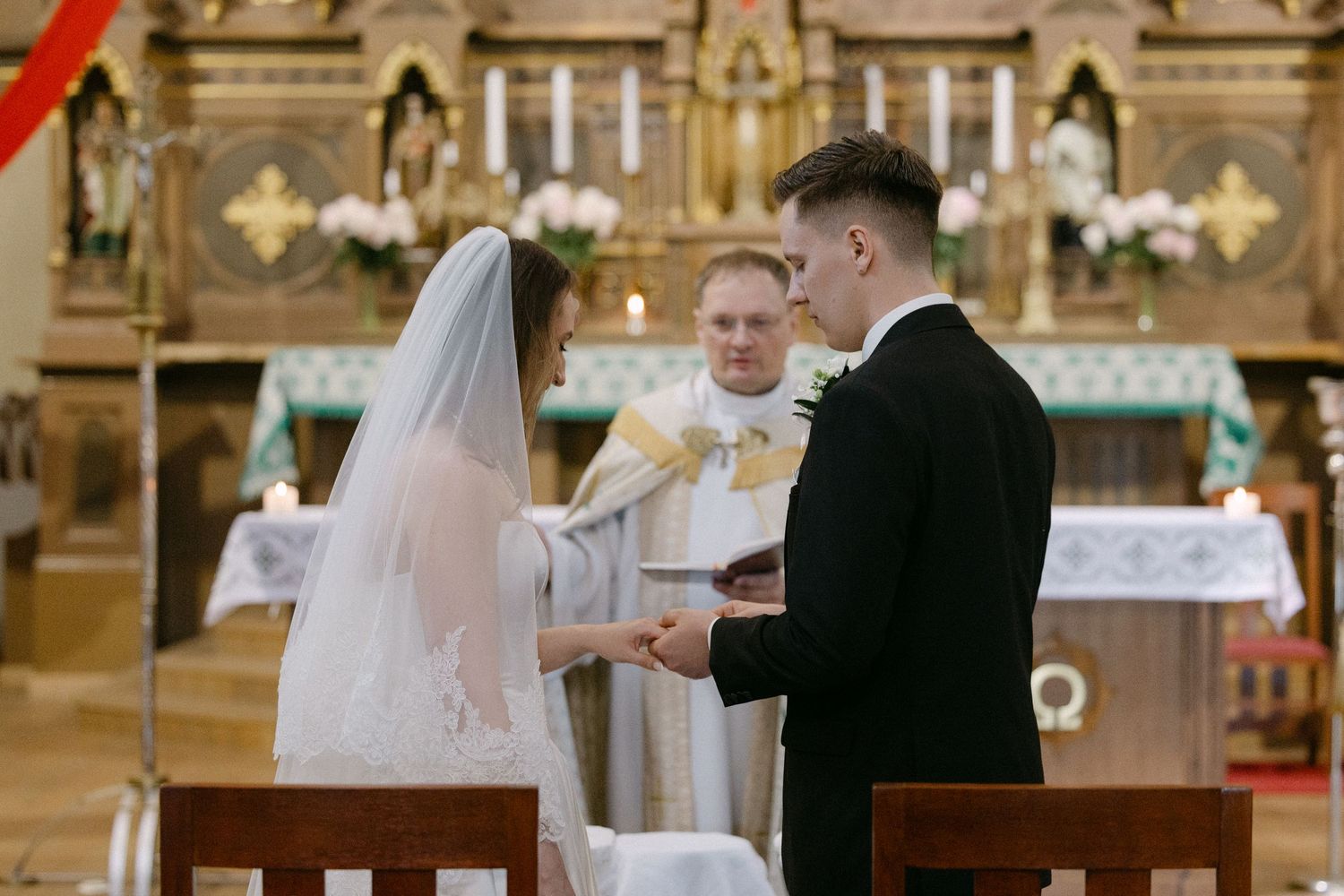 Bride and groom exchange vows at a church altar with a priest officiating during a traditional wedding ceremony.