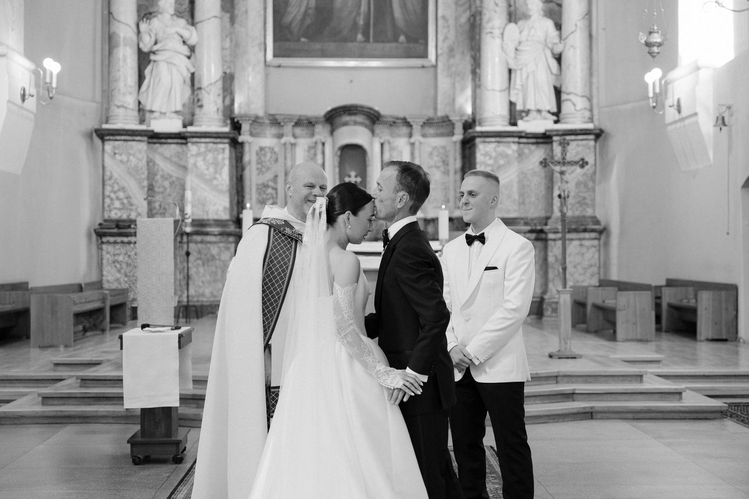Bride and groom exchanging vows at the altar in a classic church wedding ceremony, black and white photo.
